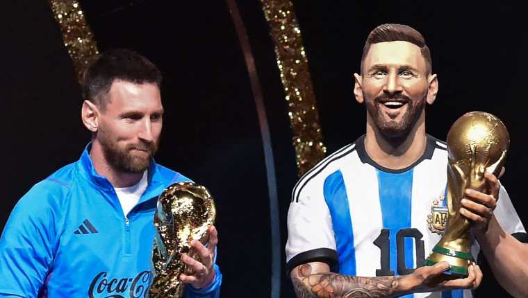 El delantero argentino Lionel Messi se encuentra junto a una estatua de sí mismo durante un homenaje de Conmebol a Argentina por su título de la Copa Mundial de Qatar 2022, celebrado antes del sorteo de las fases de grupos de los torneos de fútbol Libertadores y Sudamericana, en la sede de Conmebol. Foto Prensa Libre (AFP)