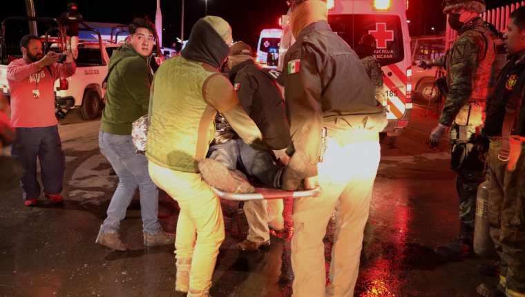 Policías trasladan a un migrante quemado en el incendio en un albergue para migrantes en Ciudad Juarez, México, que dejó 39 muertos. (Foto Prensa Libre: AFP)