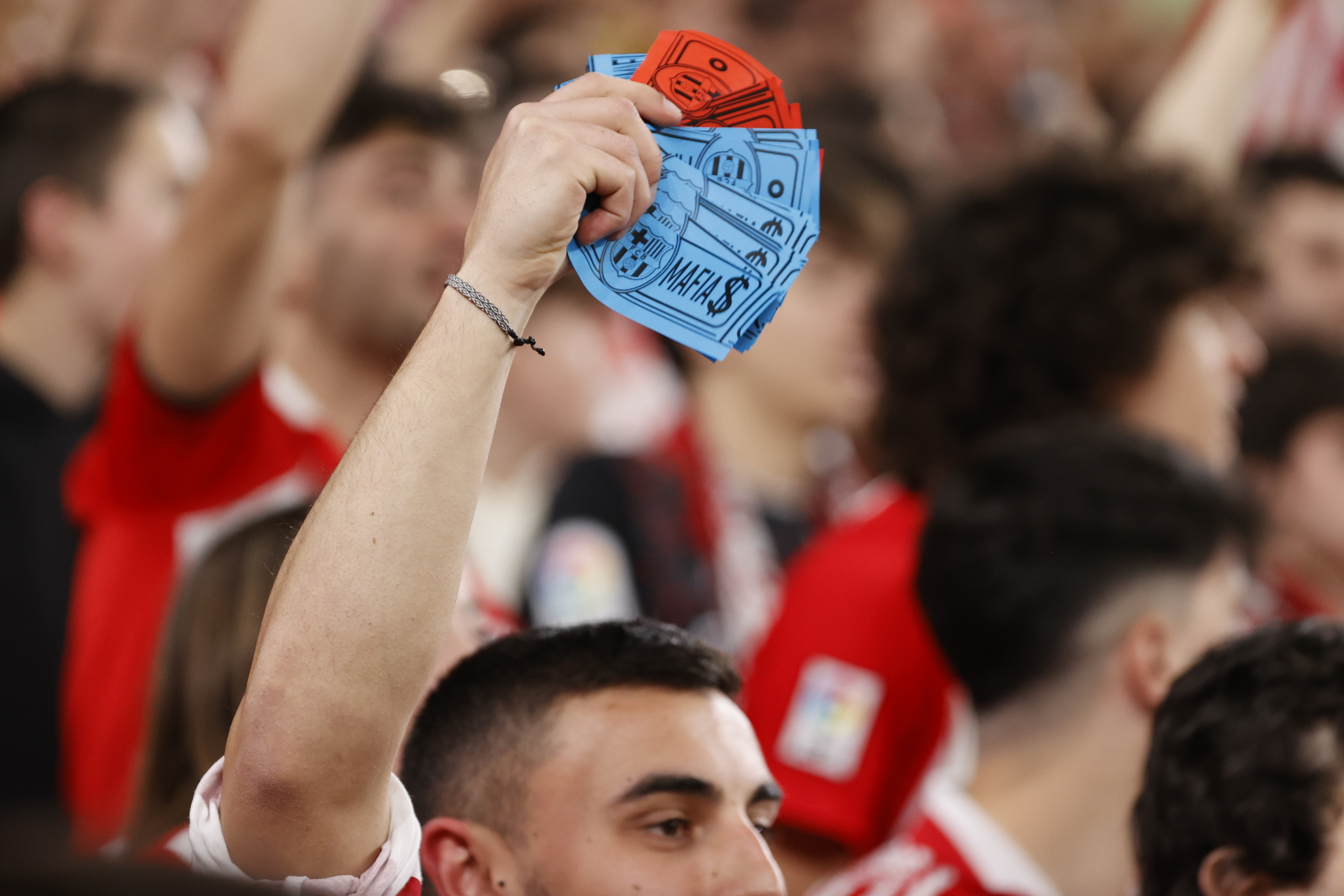 Un joven con billetes con el escudo del FC Barcelona y la palabra "mafia" durante el encuentro correspondiente a la jornada 25 de primera división que disputan hoy domingo en el estadio de San Mamés. Foto Prensa Libre (EFE)