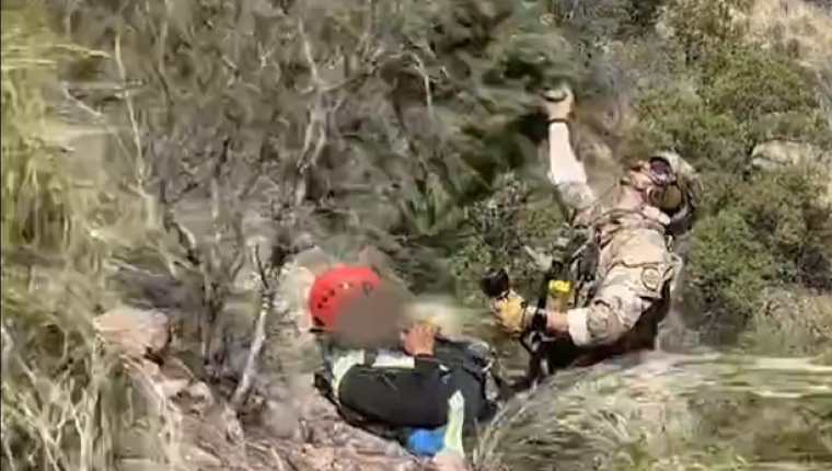 Un agente de la Patrulla Fronteriza de EE. UU. asegura a un joven guatemalteco para llevarlo a un helicóptero, luego de haber silo localizado en un desierto de Arizona. (Foto Prensa Libre: captura de pantalla del video de @USBPChiefTCA)