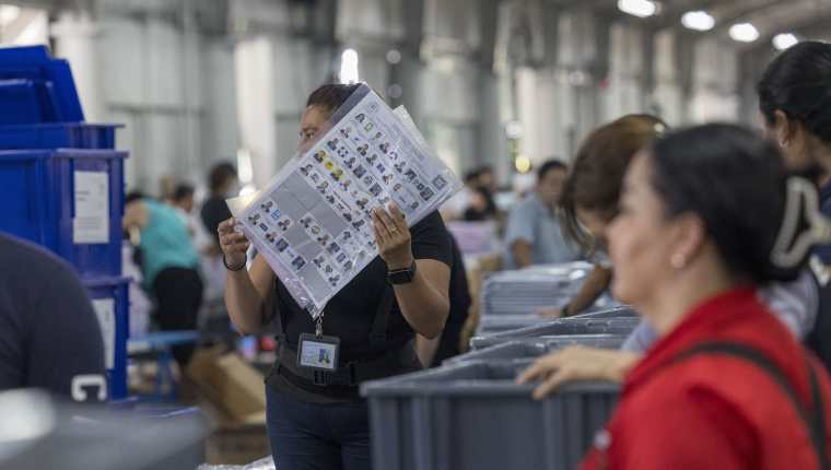 Personal del TSE empacan las boletas que se utilizarán en la elección de hoy. (Foto Prensa Libre: EFE)