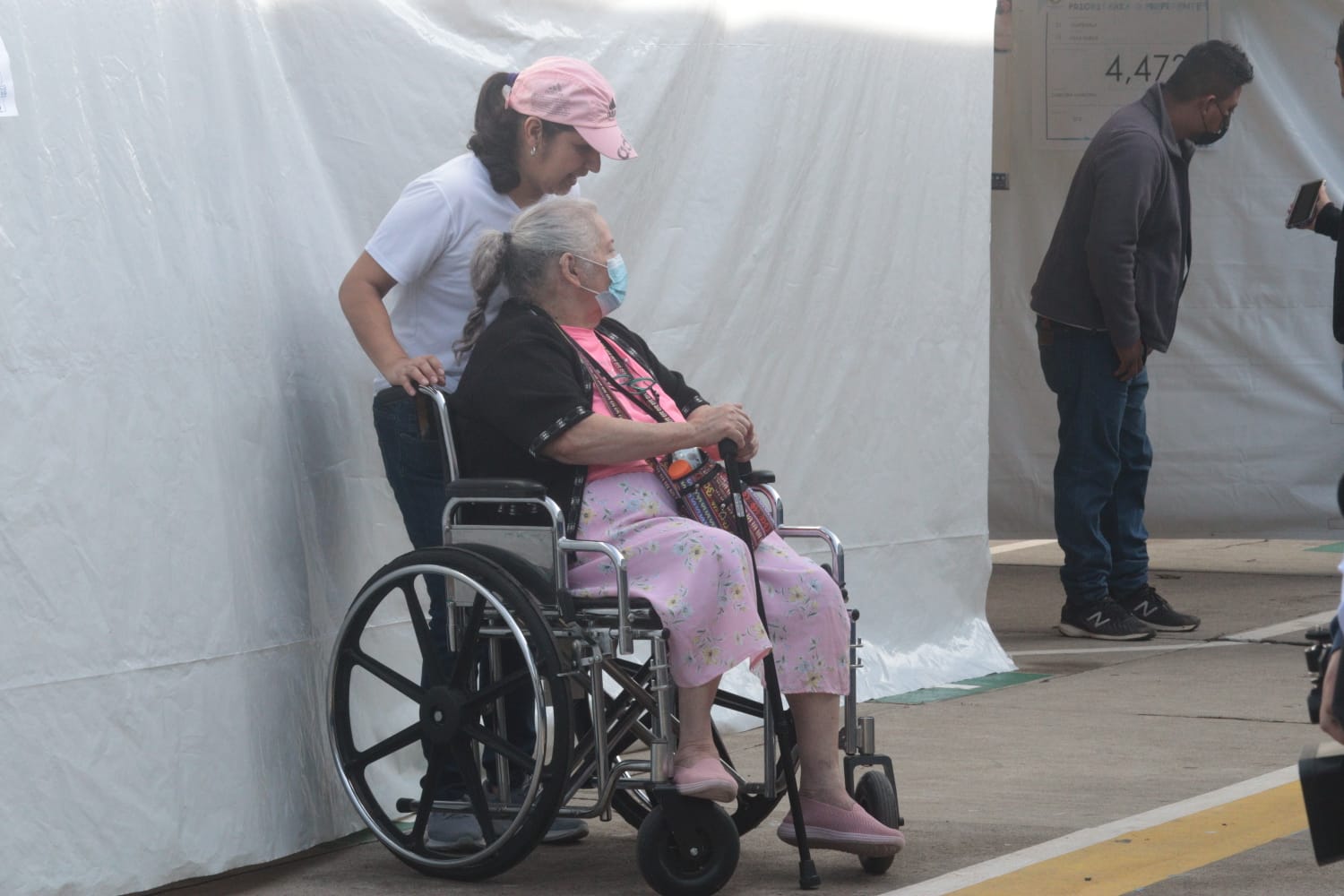 Persona con discapacidad es ayudada por personal del centro de votación'