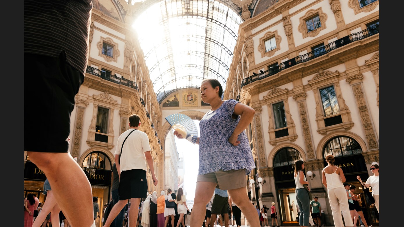 Una mujer se abanica mientras camina por el centro comercial Galleria Vittorio Emanuele en Milán, Italia, el lunes 17 de julio de 2023. (Camilla Ferrari/The New York Times)