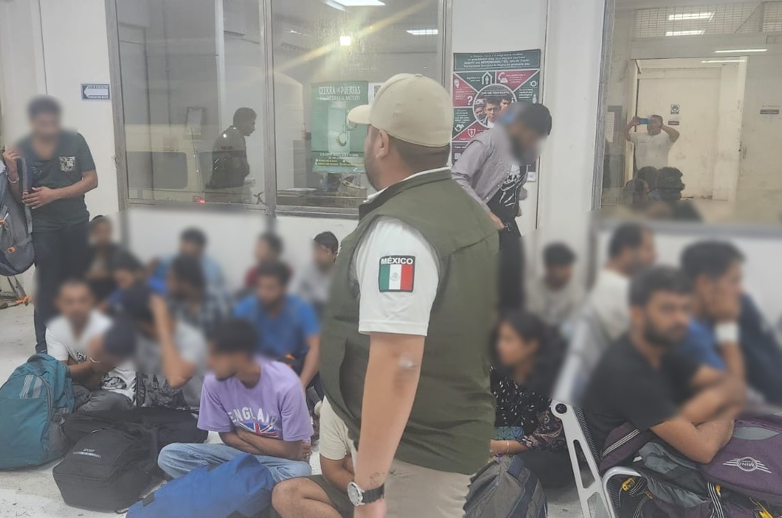 Un oficial del Instituto Nacional de Migración de México resguarda a un grupo de migrantes que fueron interceptados en Cancún. (Foto: INM)