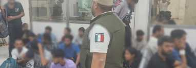 Un oficial del Instituto Nacional de Migración de México resguarda a un grupo de migrantes que fueron interceptados en Cancún. (Foto: INM)