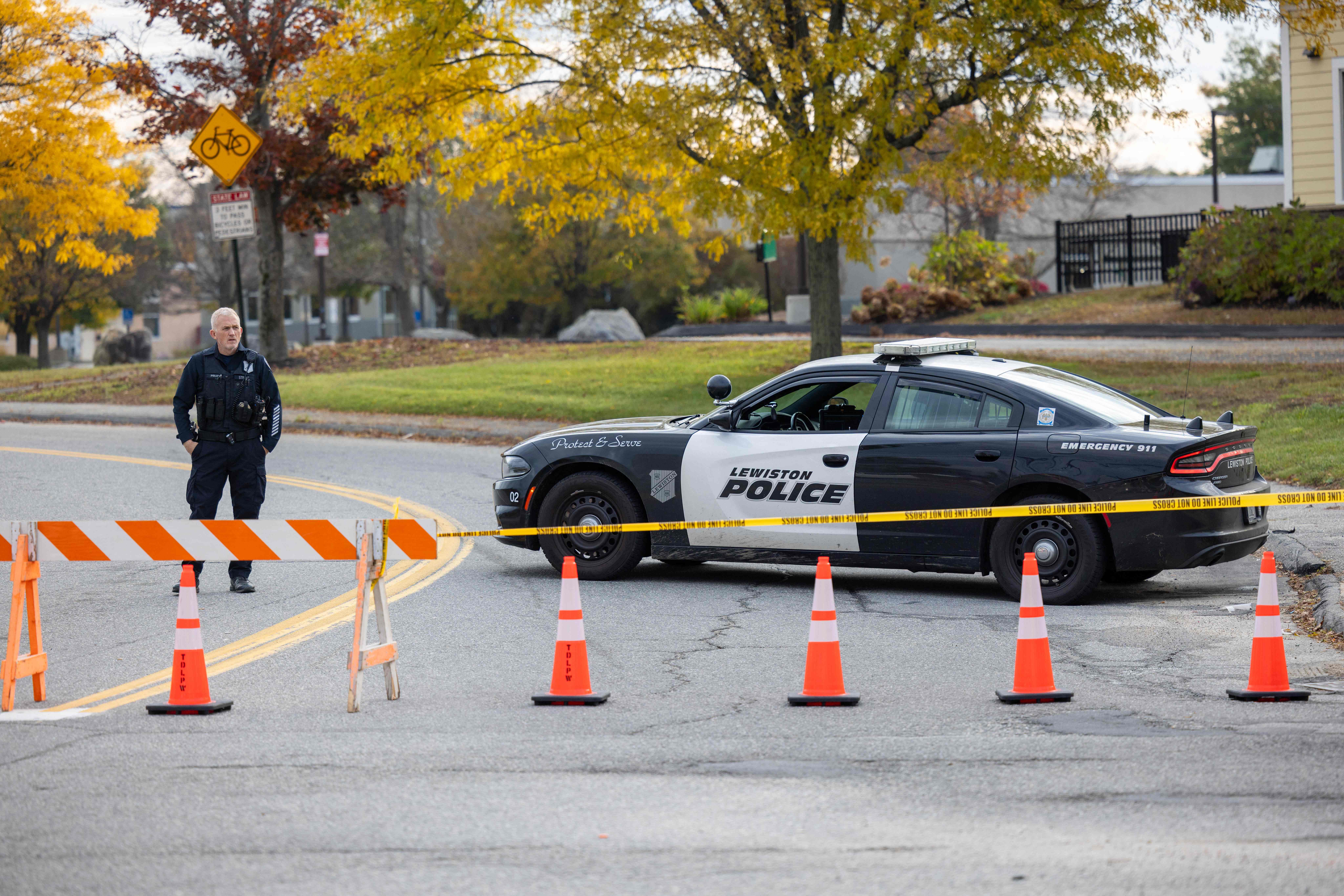 Un oficial de la Policía bloquea el acceso al camino hacia Sparetime Recreation en Lewiston, Maine, en donde se busca a Robert Card, sospechoso de una masacre que dejó 20 muertos en esa localidad. (Foto Prensa Libre: AFP)