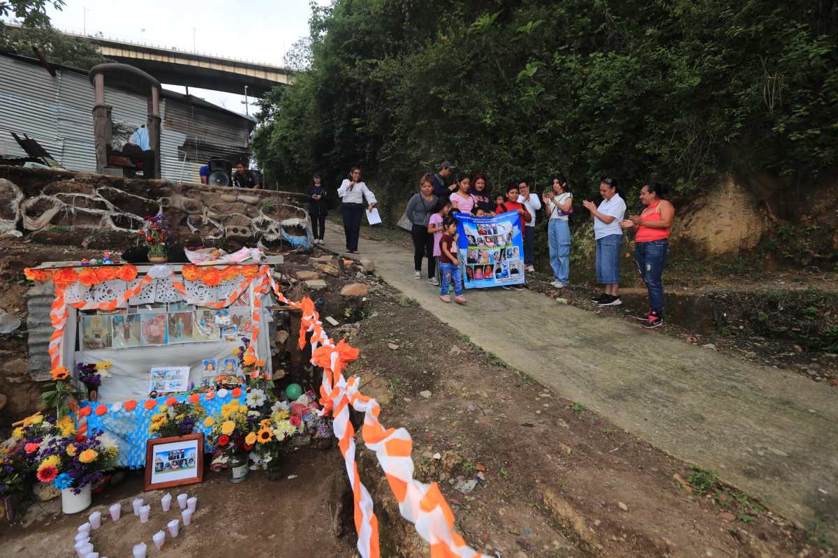 Vecinos del asentamiento Dios es Fiel, bajo el puente El Naranjo, recuerdan a las víctimas de desbordamiento de un río. (Foto Prensa Libre: Élmer Vargas)