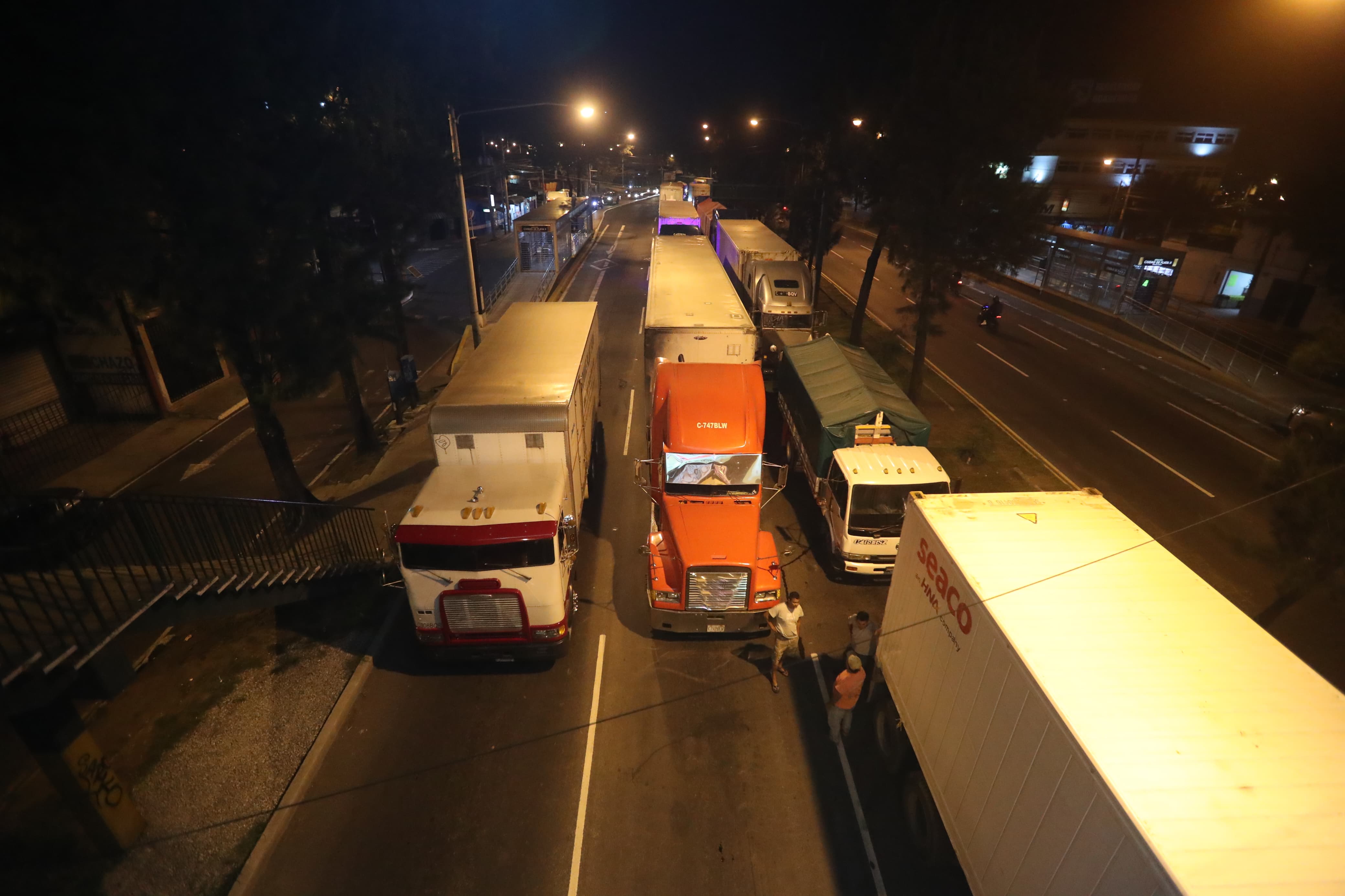 Decenas de camiones permanecen a la espera que les permitan el paso por un carril en el Periférico la noche del sábado 14 de octubre de 2023.'