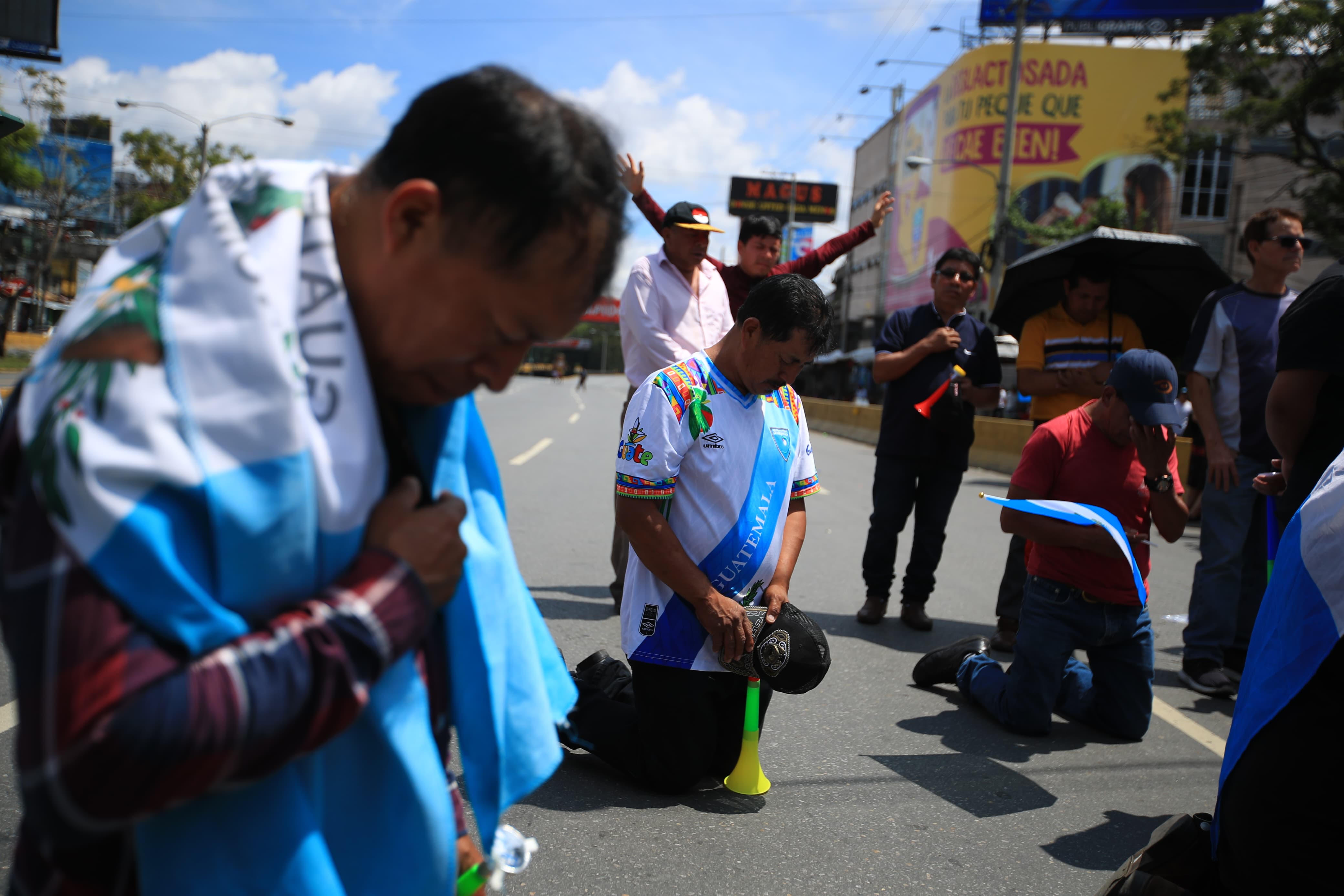 Comerciantes del mercado El Guarda, que bloquean una área de la calzada Roosevelt, realizan una oración para pedir fuerzas y seguir adelante con la solicitud de renuncia de las autoridades. (Foto Prensa Libre: Carlos Hernández Ovalle).