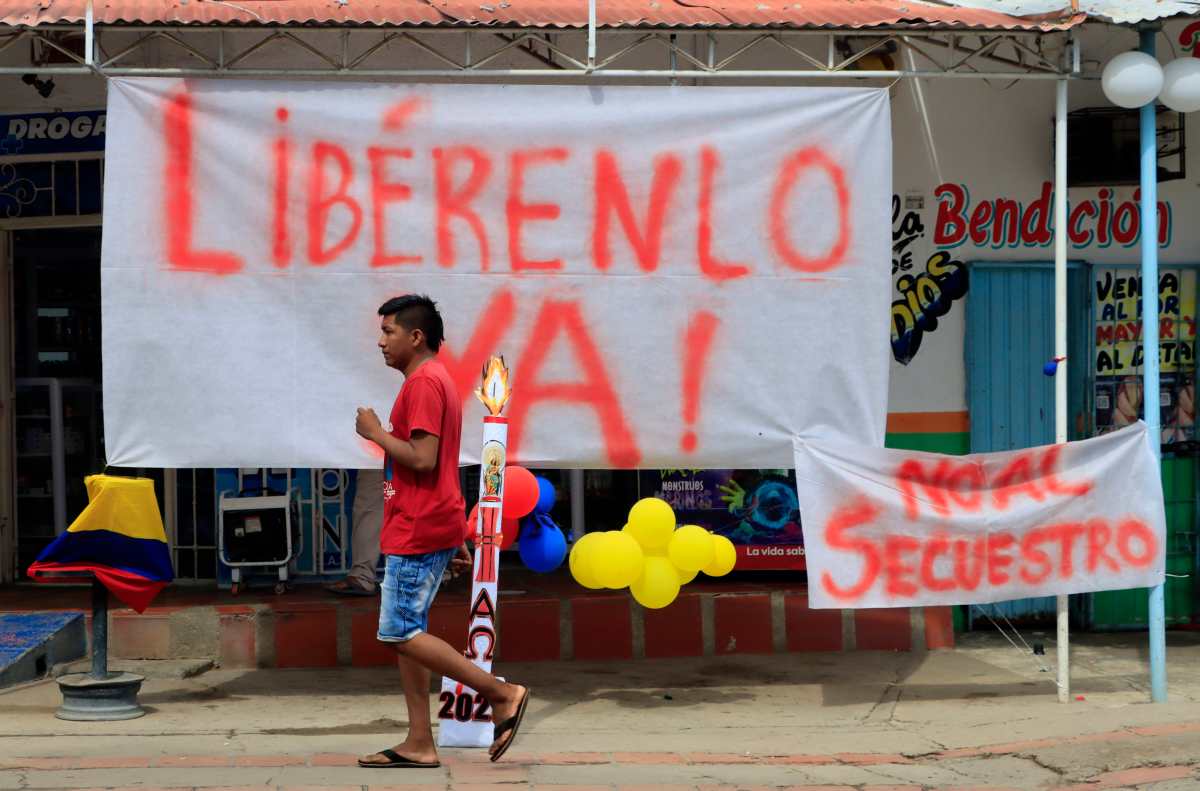 Un hombre camina hoy frente a carteles que piden la libertad y rechazan el secuestro de Luis Manuel Díaz, padre del delantero de la selección colombiana de fútbol y del club inglés Liverpool, Luis Díaz. (Foto Prensa Libre: EFE)