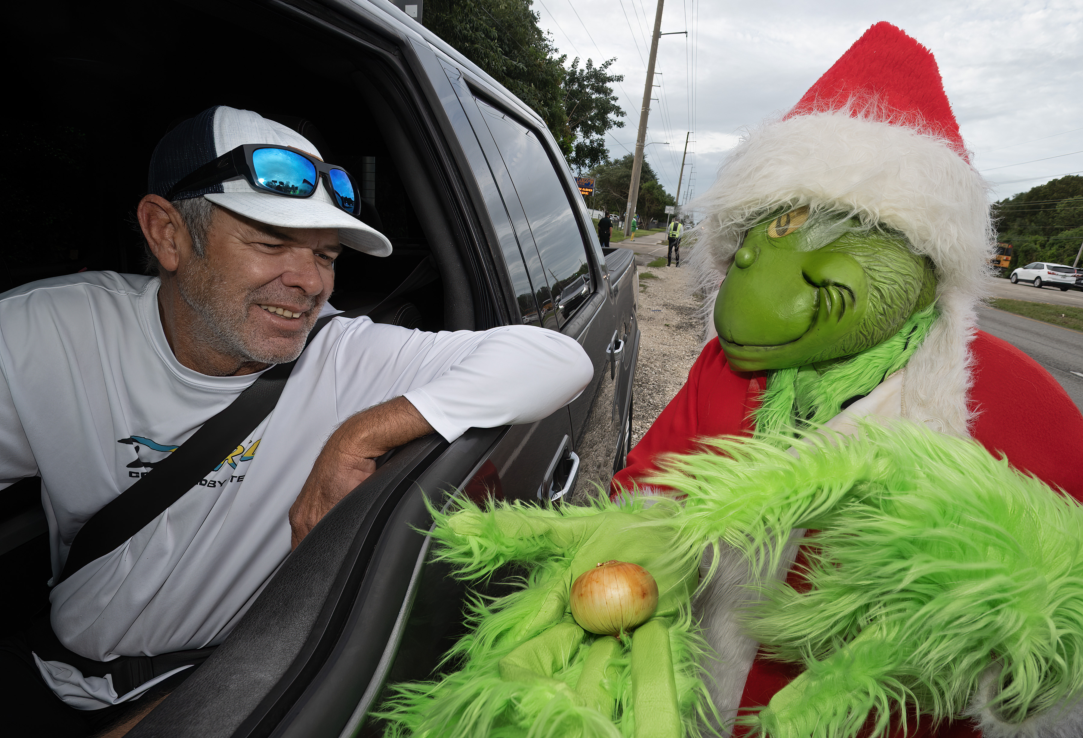 El coronel de la Oficina del Alguacil del Condado de Monroe, Lou Caputo ofrece una cebolla a un conductor en la autopista cercana a la escuela primaria Key Largo en Florida. (Foto Prensa Libre: EFE)