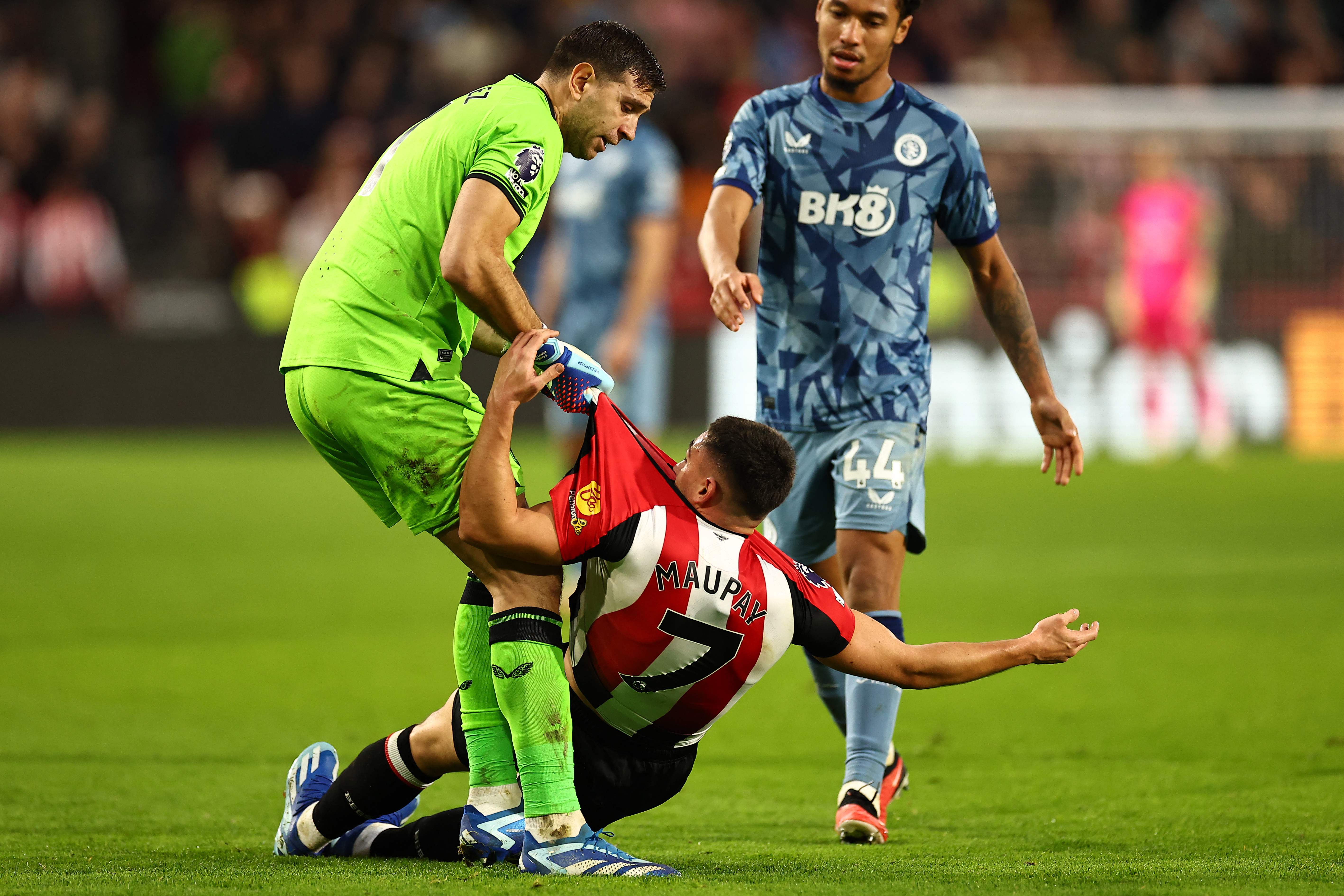 El portero del Aston Villa, Emiliano Martínez (verde), se enfrenta a su rival del Brentford, Neal Maupay. (Foto Prensa Libre: AFP)