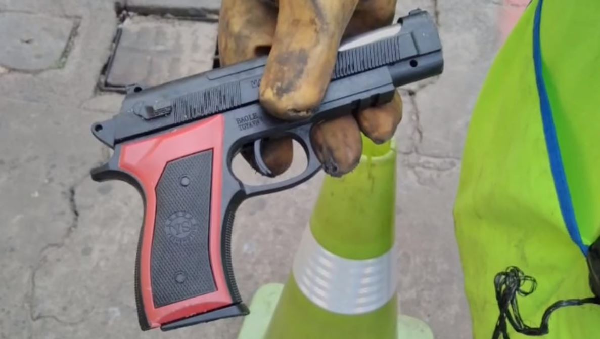 La pistola de juguete que fue abandonada por un motorista en la zona 1 de la capital fue desechada por personal de limpieza de la comuna capitalina. (Foto Prensa Libre: Captura de pantalla)