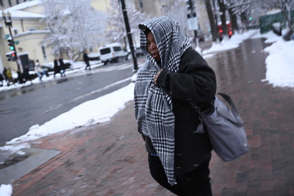 Una mujer intenta cubrirse mientras camina en las calles de Washington, una de las regiones azotadas por la tormenta invernal.