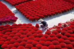 In this photo taken on January 20, 2024 a worker prepares incense sticks in a courtyard in the village of Quang Phu Cau on the outskirts of Hanoi. Families living and working in the "incense village" of Quang Phu Cau now also make sticks in yellow, blue and green, catering to visitors eager to snap shots for Instagram. (Photo by Nhac NGUYEN / AFP)