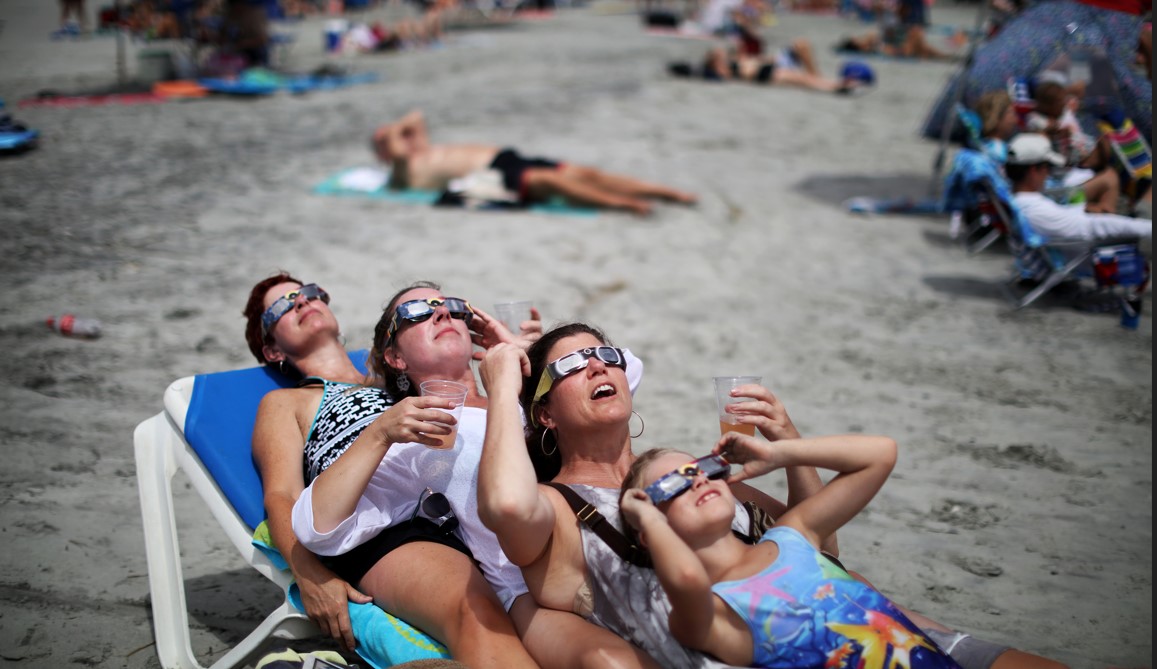 Un grupo de bañistas ve el eclipse solar en Folly Beach, Carolina del Sur, el 21 de agosto de 2017. (Travis Dove/The New York Times)