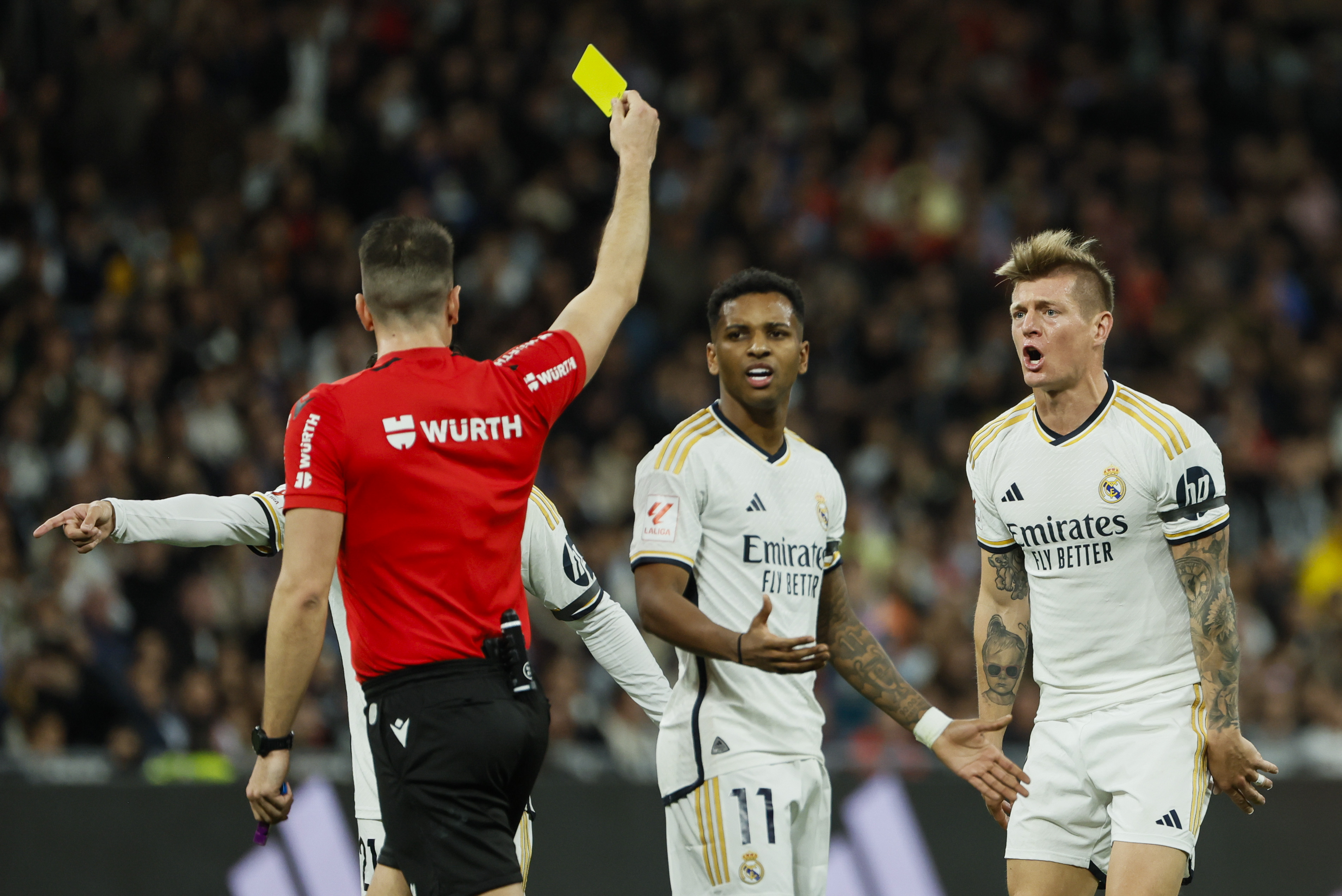 El árbitro Díaz de Mera Escuderos (i) muestra la tarjeta amarilla a Toni Kroos (d), del Real Madrid, durante el partido contra el Sevilla FC en el estadio Santiago Bernabéu. (Foto Prensa Libre: EFE)