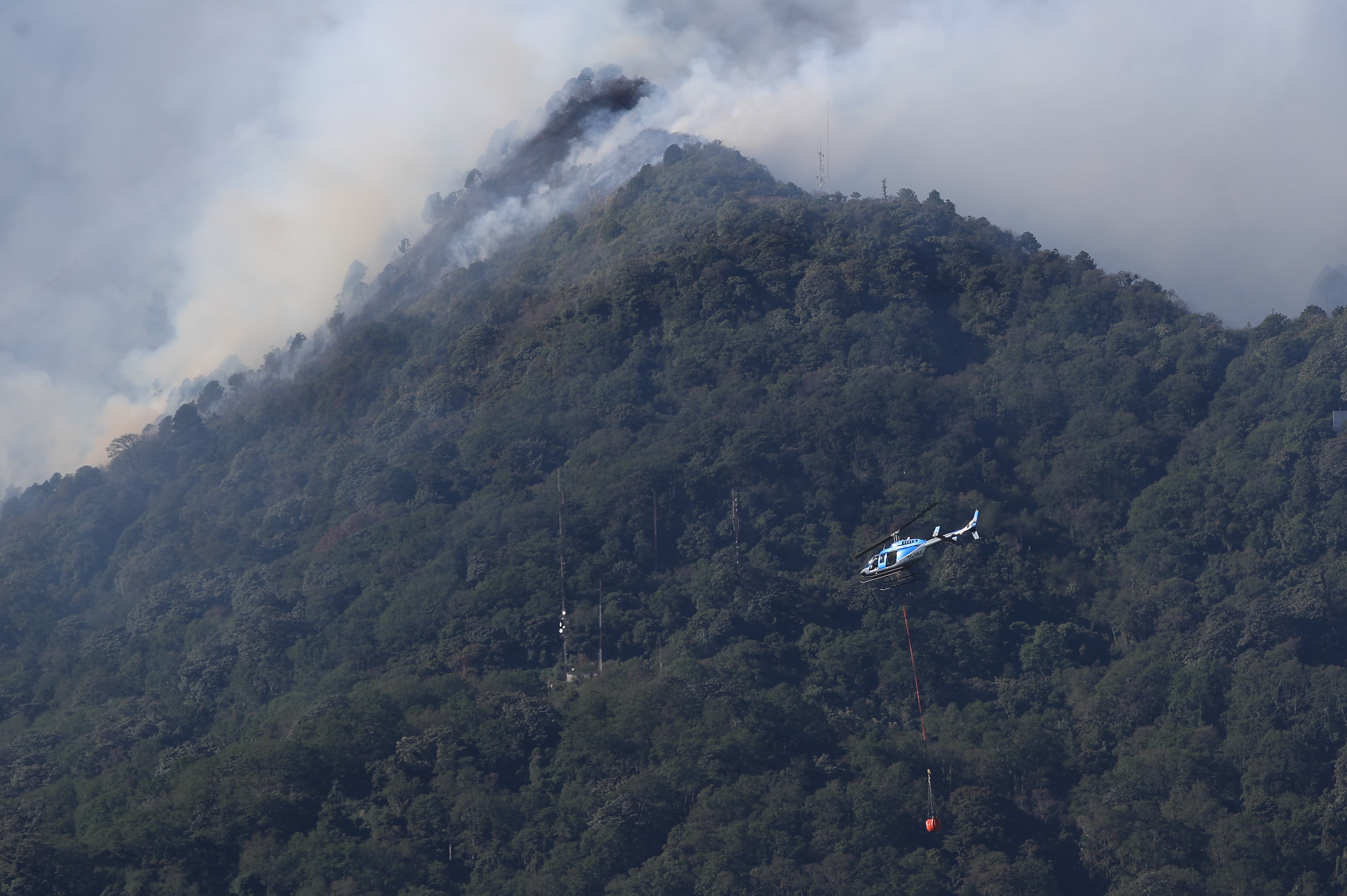 Helicóptero equipado con sistema bambi bucket, un balde especializado suspendido en un cable para entregar agua y combatir el incendios en el Volcán de Agua. (Foto Prensa Libre: Carlos Hernández)