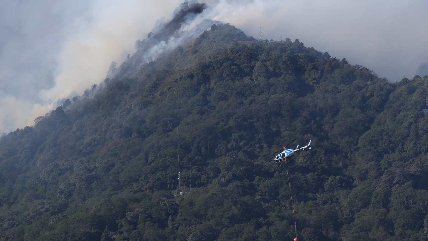 Helicóptero equipado con sistema bambi bucket, un balde especializado suspendido en un cable para entregar agua y combatir el incendios en el Volcán de Agua. (Foto Prensa Libre: Carlos Hernández)