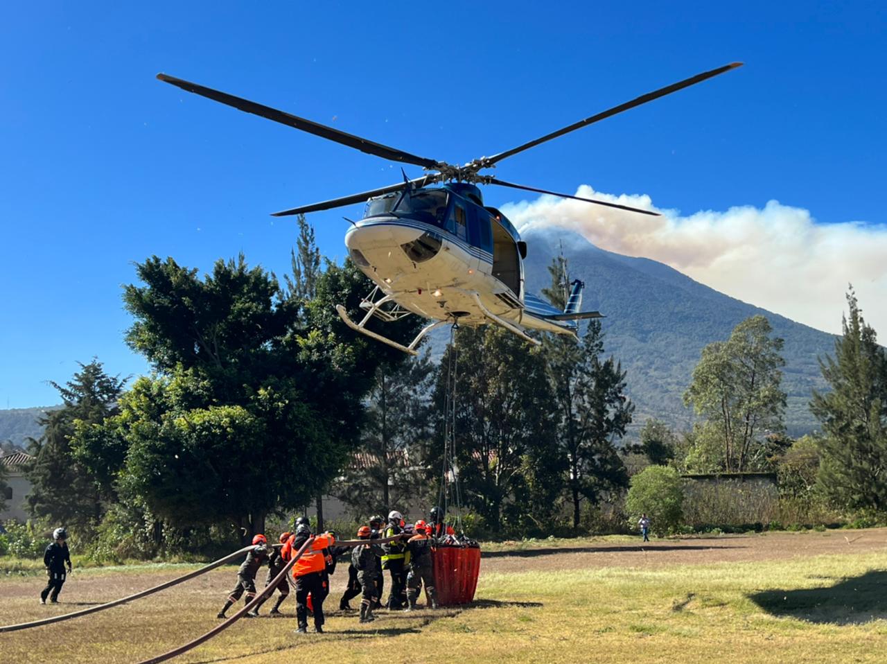 Un helicóptero de la FAG, con bambi bucket, es abstecido por Bomberos Voluntarios para el combate del incendio en el Volcán de Fuego. (Foto Prensa Libre: Ejército de Guatemala)