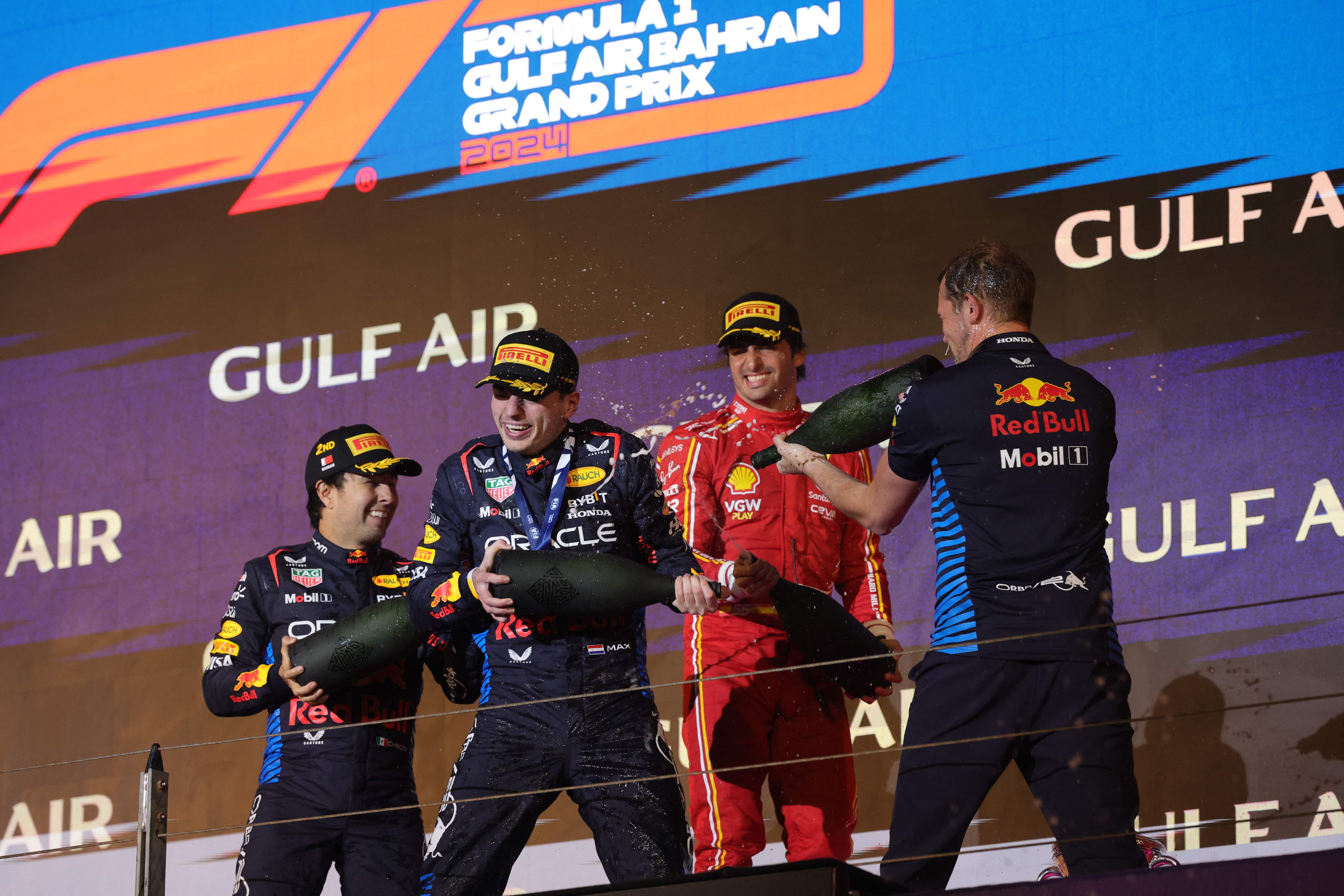 El primer clasificado de la carrera, Max Verstappen (Segundo Izquierda), junto a su compañero de Red Bull, y segundo clasificado Sergio Perez (Izq), al lado del tercer lugar, Carlos Sainz Jr (Sengundo Derecha) celebrando durante la ceremonioa del podio en el Gran Premio de Bahréin en la Fórmula 1. (Foto Prensa Libre: AFP)