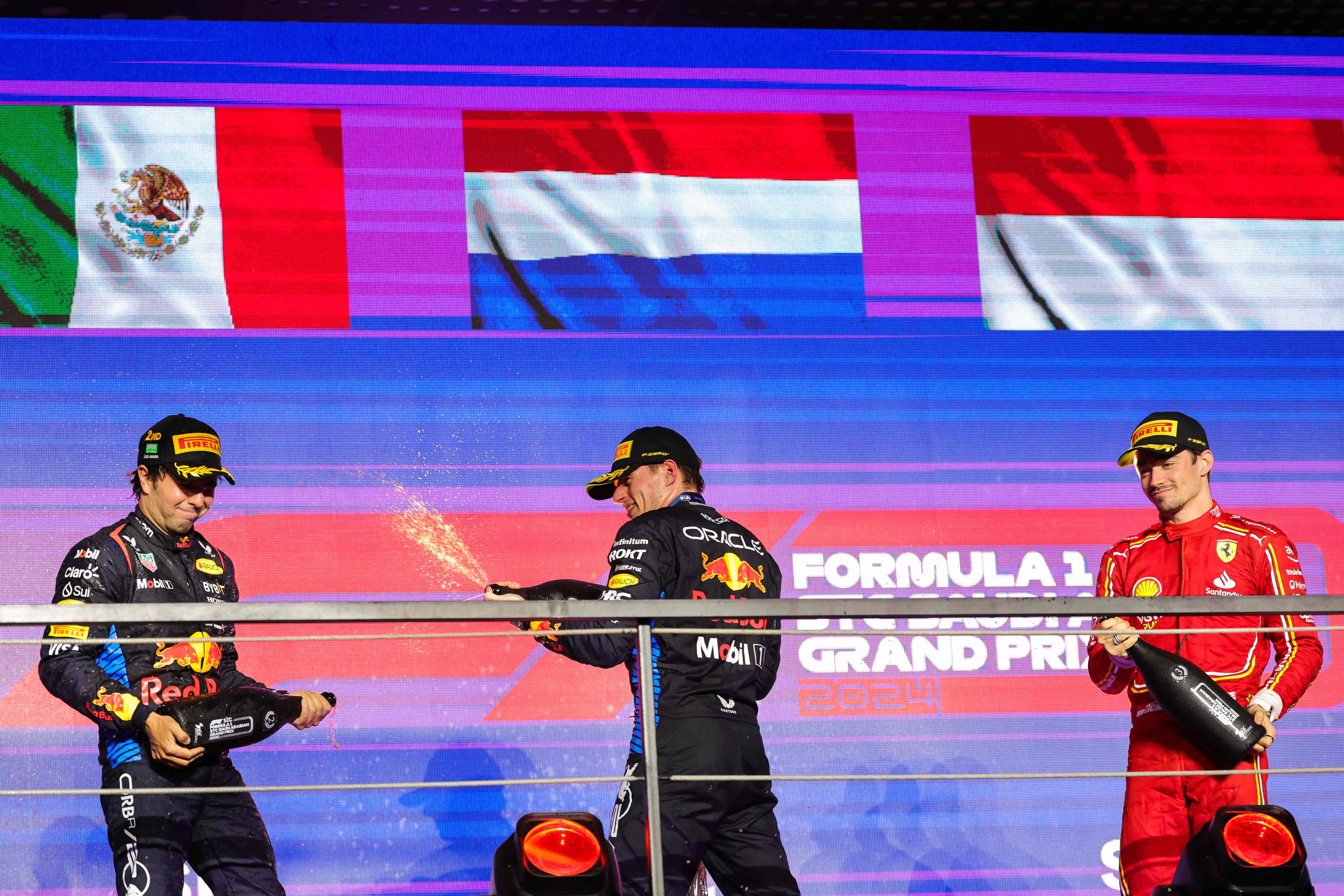 El piloto neerlandés de Red Bull, Max Verstappen, celebra su victoria en el GP de Arabi Saudita, rociando de champagne a su compañero de equipo, el mexicano, Sergio Perez, compartiendo podio con el monegasco, Charles Leclerc (der). (Foto Prensa Libre: AFP)