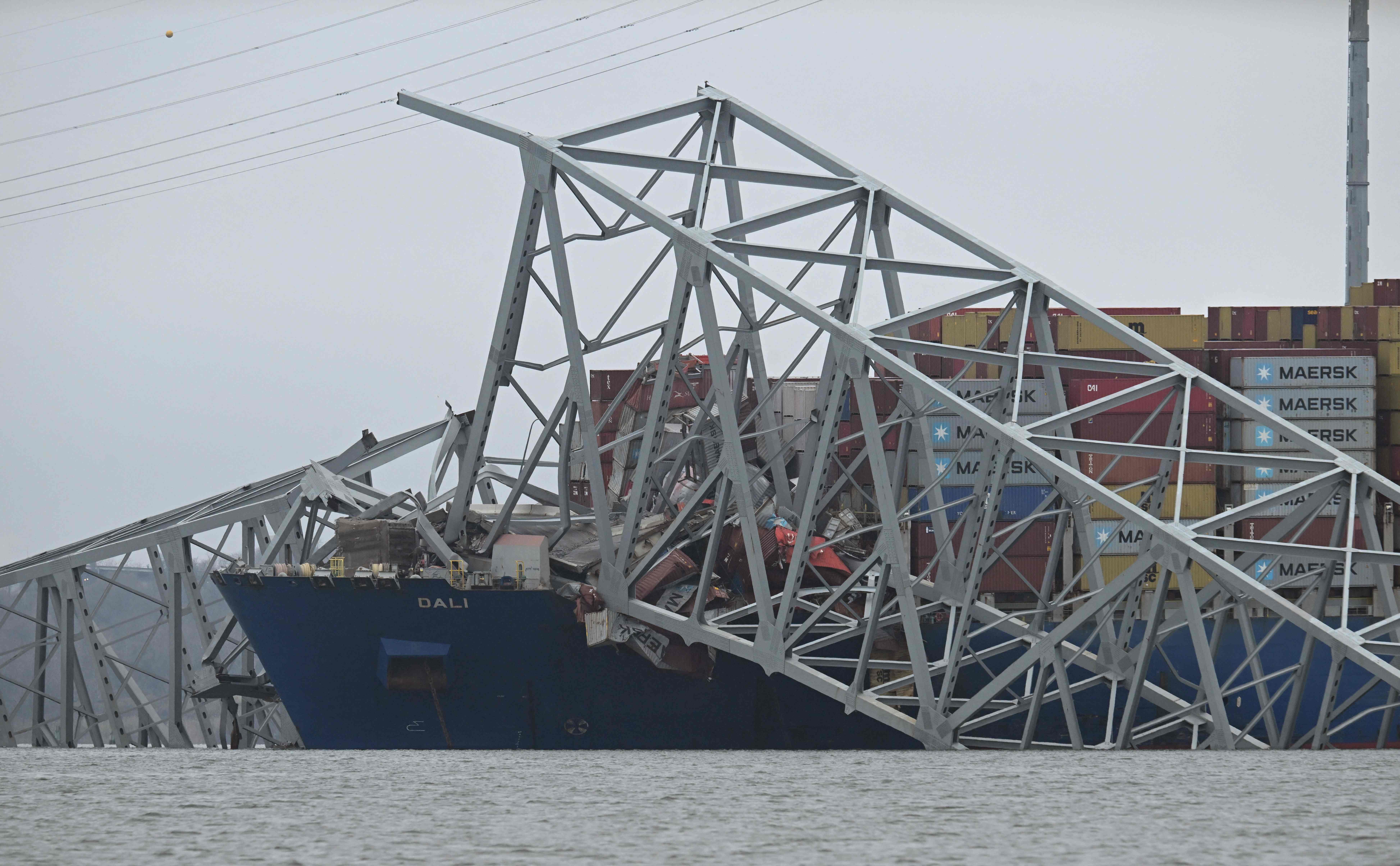The collapsed Francis Scott Key Bridge lies on top of  the container ship Dali in Baltimore, Maryland, on March 27, 2024. Authorities in Baltimore were set to focus on expanding recovery efforts on March 27 after the cargo ship slammed into the bridge, causing it to collapse and leaving six people presumed dead. All six were members of a construction crew repairing potholes on the bridge when the structure fell into the Patapsco River at around 1:30 am (0530 GMT) on March 26. (Photo by Jim WATSON / AFP)