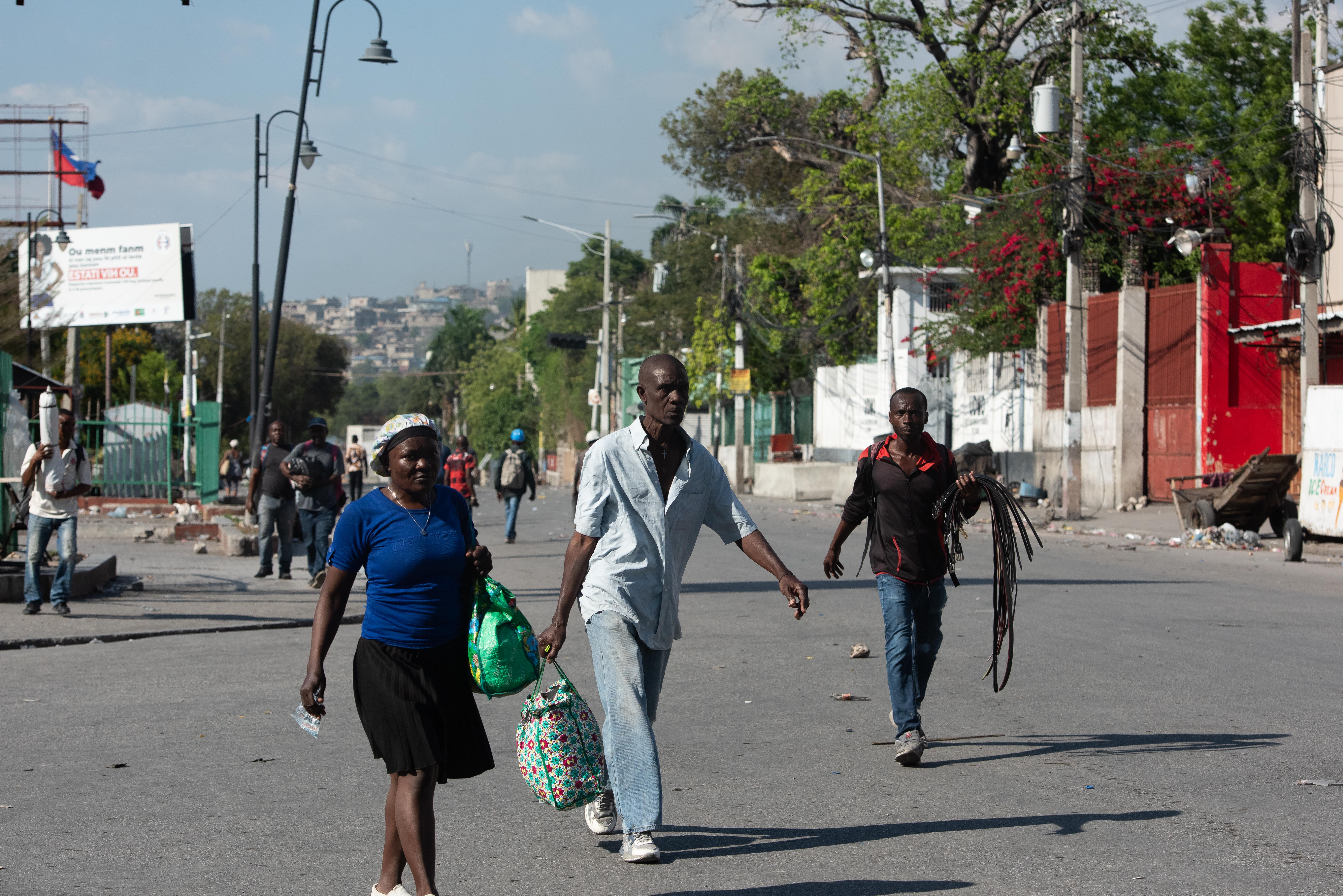 Varias personas abandonan Champs de Mars, muy cerca del Palacio Nacional, donde se registran intensos tiroteos en la zona y duros enfrentamientos entre pandilleros y la Policía, en Puerto Príncipe, Haití.  (Foto Prensa Libre: EFE)