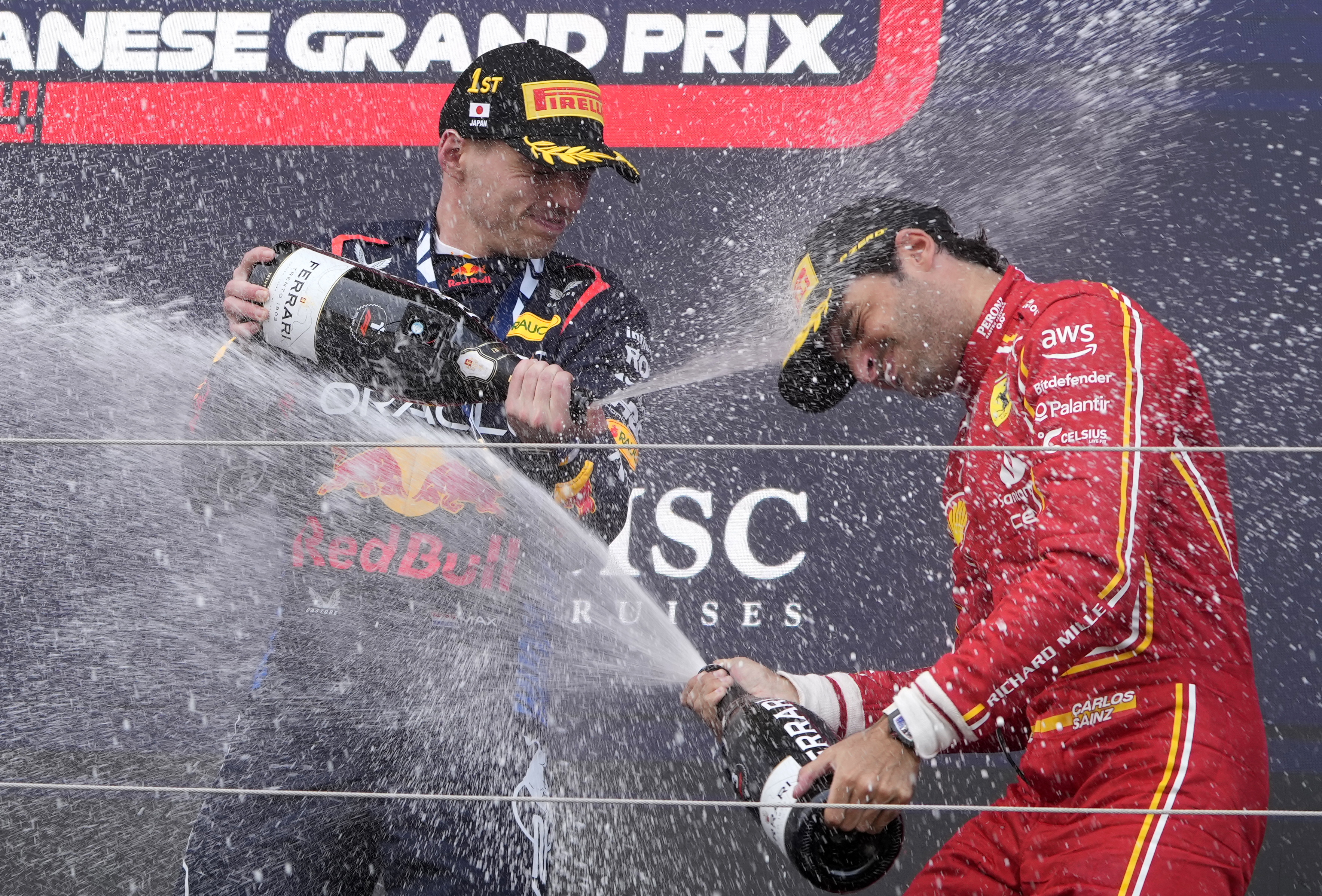 El piloto español de Ferrari Carlos Sainz Jr. (C), tercero, celebra en el podio con el holandés Max Verstappen (i), vencedor, durante la entrega de trofeos del Gran Premio de Japón de F1, este domingo, en el Circuito de Suzuka (Japón). (Foto Prensa Libre: EFE)