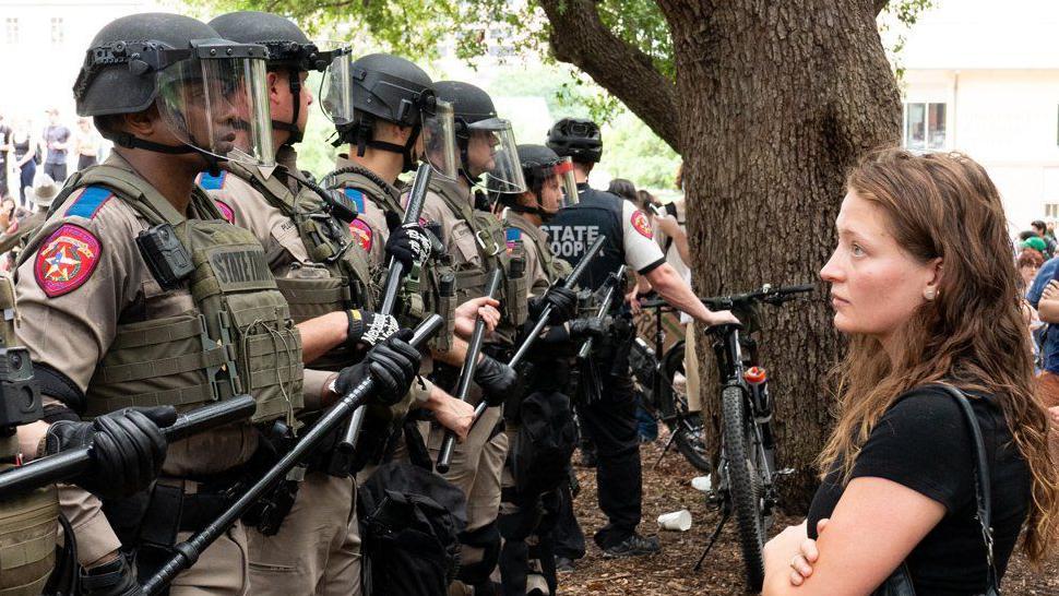 Una estudiante mira fijamente a una hilera de policías estatales de Texas durante las protestas. GETTY IMAGES