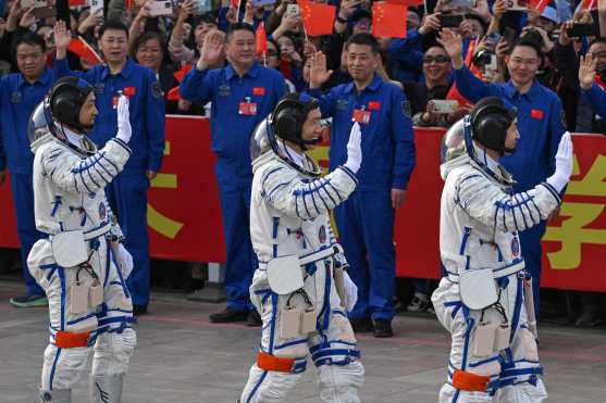 Astronauts for China's Shenzhou-18 space mission (L-R) Li Guangsu, Li Cong and Ye Guangfu wave during a departure ceremony before boarding a bus to take them to the Shenzhou-18 spacecraft at the Jiuquan Satellite Launch Centre in the Gobi desert in northwest China on April 25, 2024. (Photo by GREG BAKER / AFP)