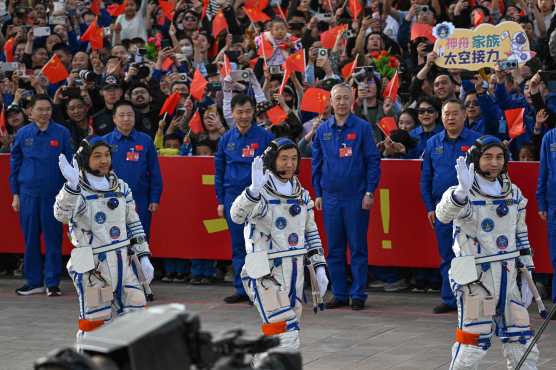 Astronauts for China's Shenzhou-18 space mission (L-R) Li Guangsu, Li Cong and Ye Guangfu wave during a departure ceremony before boarding a bus to take them to the Shenzhou-18 spacecraft at the Jiuquan Satellite Launch Centre in the Gobi desert in northwest China on April 25, 2024. (Photo by GREG BAKER / AFP)