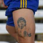 Aficionado de Boca muestra un tatuaje de Diego Maradona.