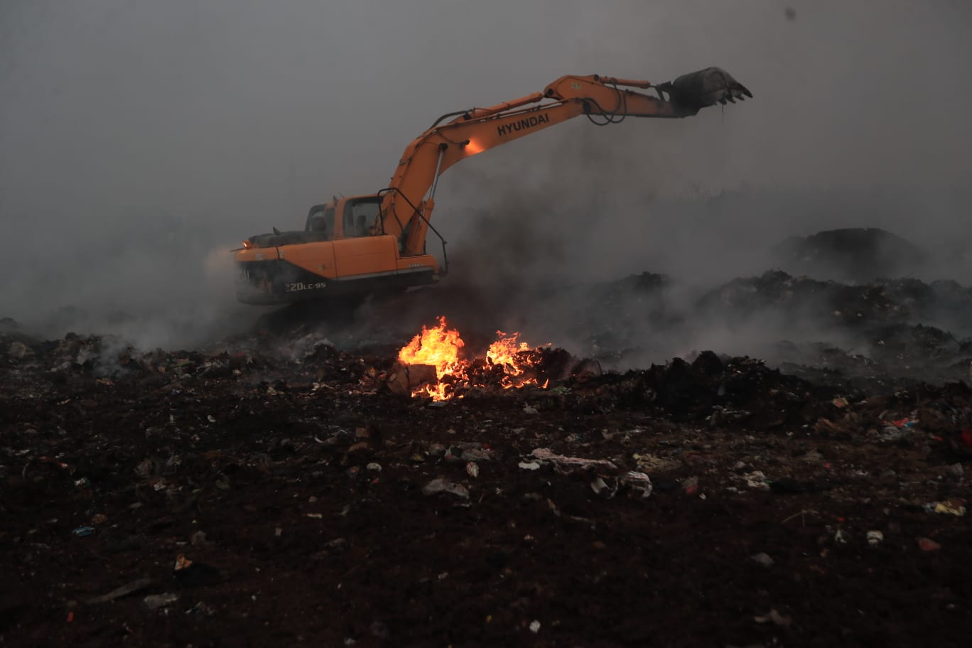 Cuerpos socorristas utilizan máquinas excavadoras para remover material inerte y cubrir residuos como parte de la estrategia para sofocar el incendio. (Foto Prensa Libre: Oscar Vásquez). 