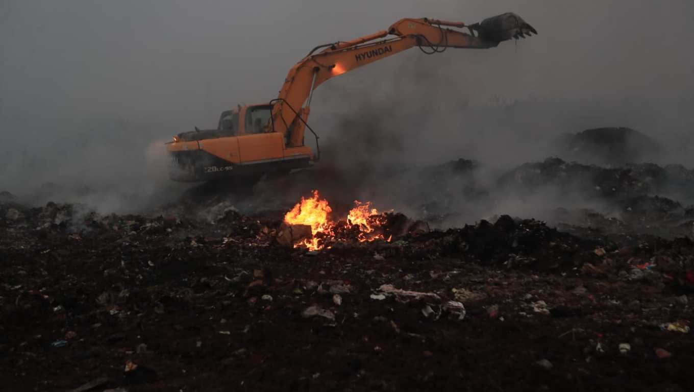 Cuerpos socorristas utilizan máquinas excavadoras para remover material inerte y cubrir residuos como parte de la estrategia para sofocar el incendio. (Foto Prensa Libre: Oscar Vásquez). 