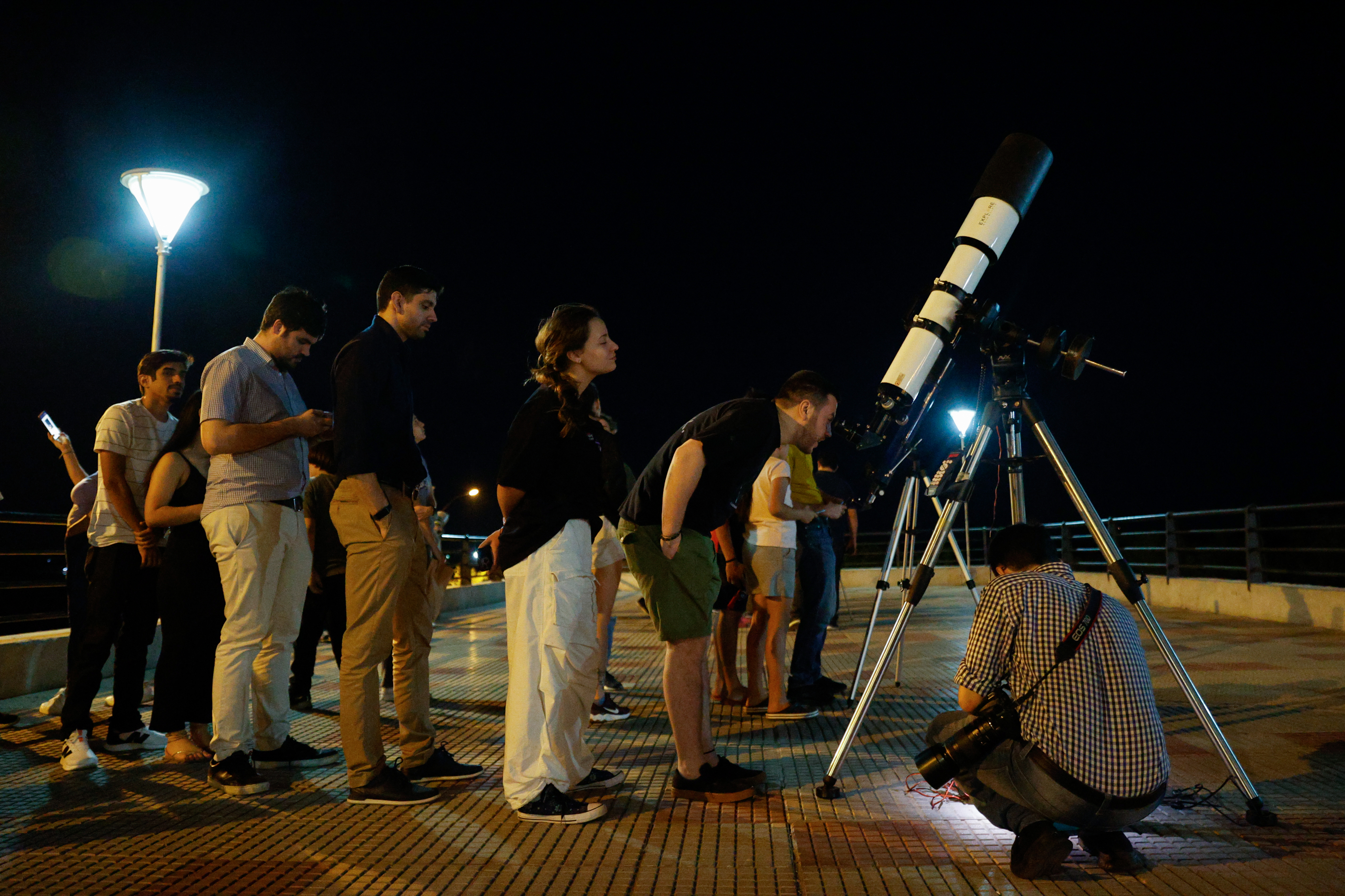 AME613. ASUNCIÓN (PARAGUAY), 17/09/2024.- Un hombre observa por un telescopio el eclipse lunar parcial este martes, en Asunción (Paraguay). EFE/ Juan Pablo Pino