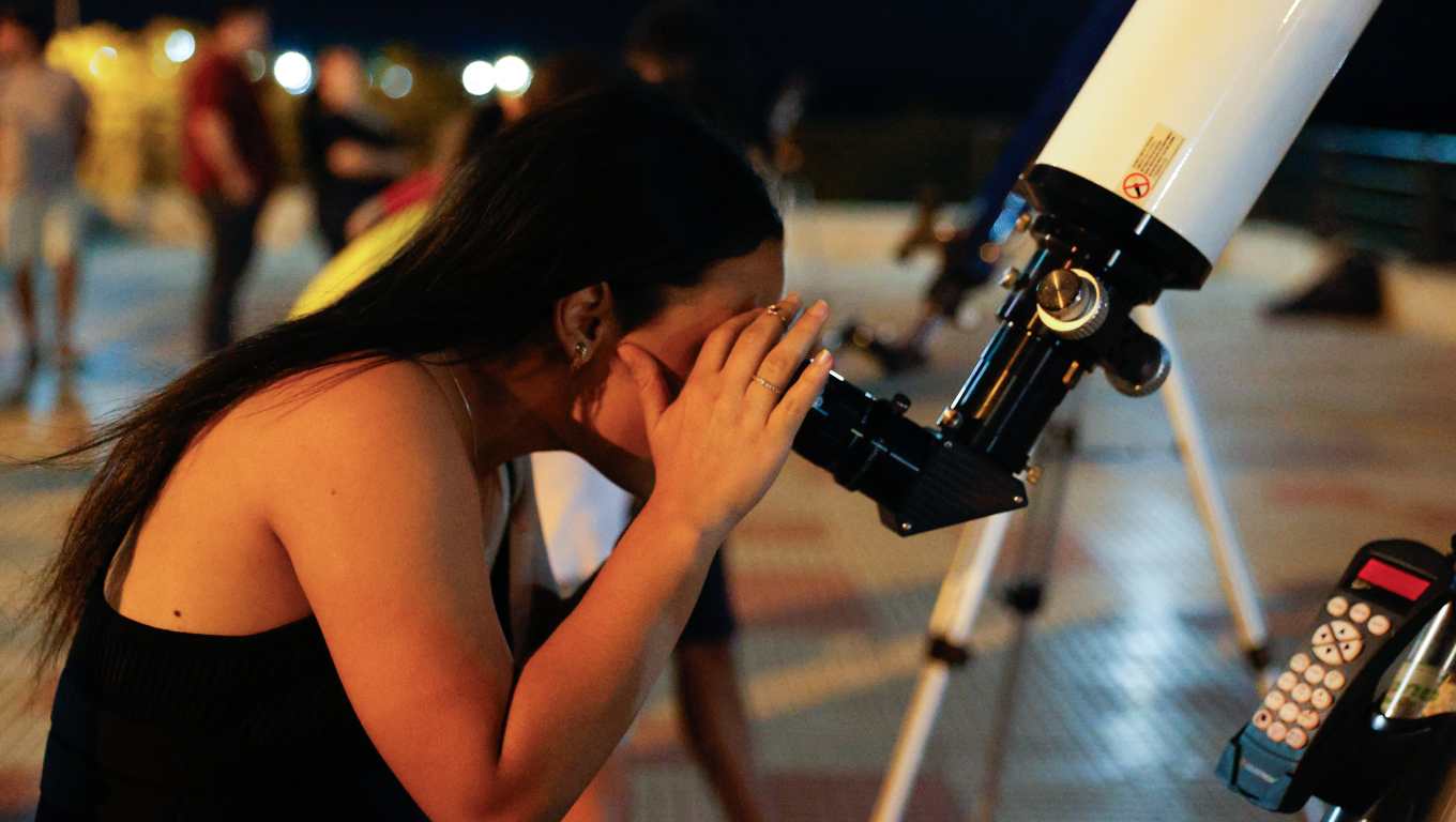 AME615. ASUNCIÓN (PARAGUAY), 17/09/2024.- Una mujer observa por un telescopio el eclipse lunar parcial este martes, en Asunción (Paraguay). EFE/ Juan Pablo Pino