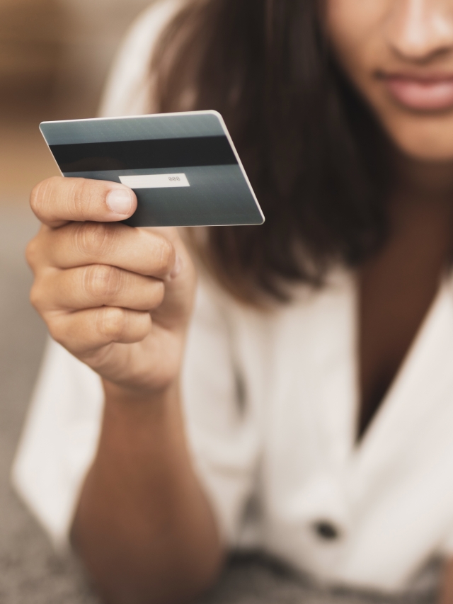 mujer sostiene con la mano derecha una tarjeta de crédito