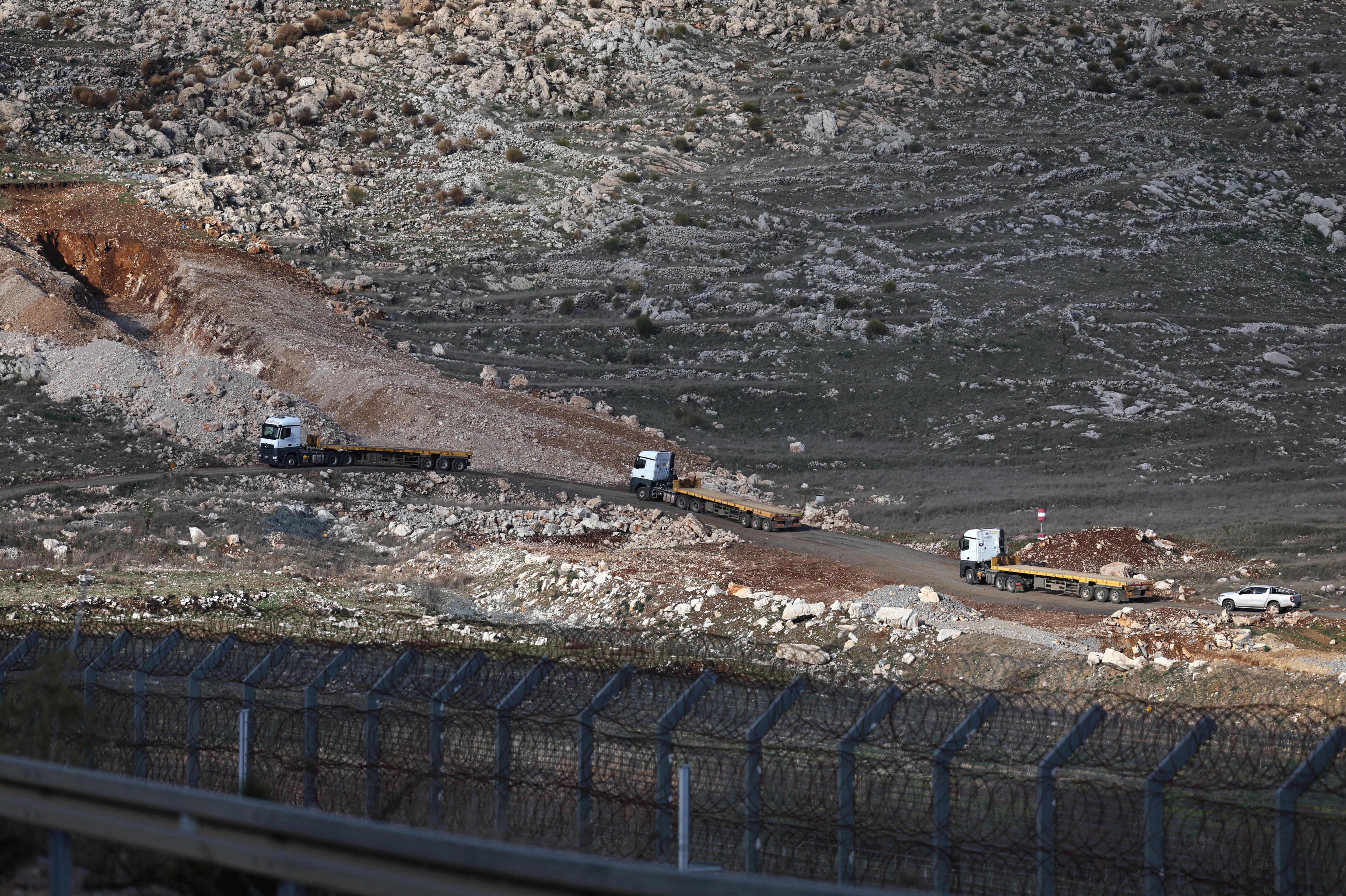 Camiones israelíes cruzan la zona de amortiguamiento entre Israel y Siria, cerca de la aldea drusa de Majdal Shams, en los Altos del Golán. (Foto Prensa Libre: EFE)