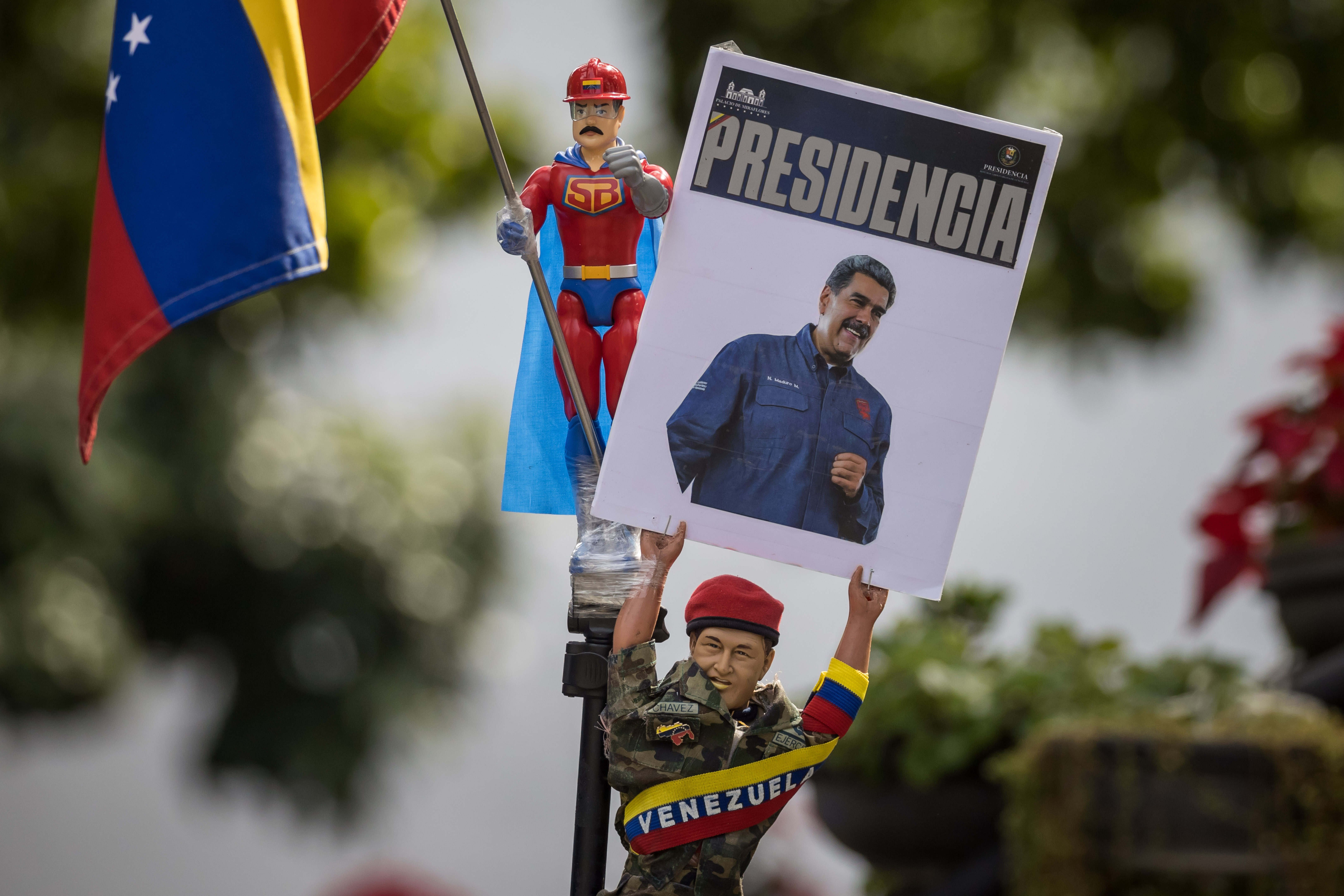 Una persona sostiene un muñeco que representa al fallecido presidente de Venezuela, Hugo Chávez, con un cartel con la imagen del presidente de Venezuela, Nicolás Maduro, en un acto por el inicio del año legislativo de la Asamblea Nacional (AN, Parlamento) de Venezuela este domingo, en Caracas (Venezuela). (Foto Prensa Libre: AFP)