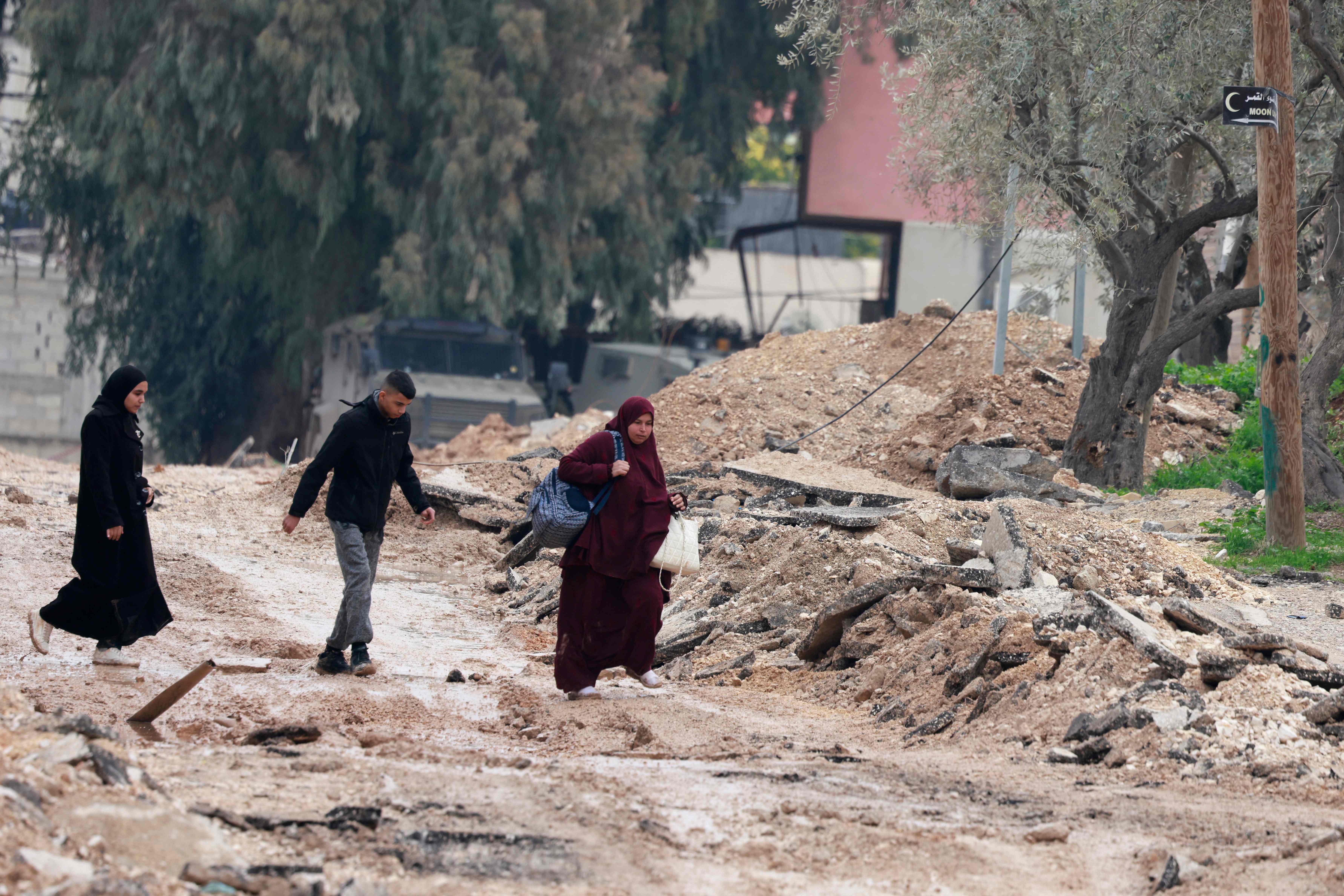Ciudadanos que caminan por una carretera destruida en Jenin han comenzado a abandonar sus hogares en una zona conflictiva del Cisjordania. (Foto Prensa Libre: AFP) 