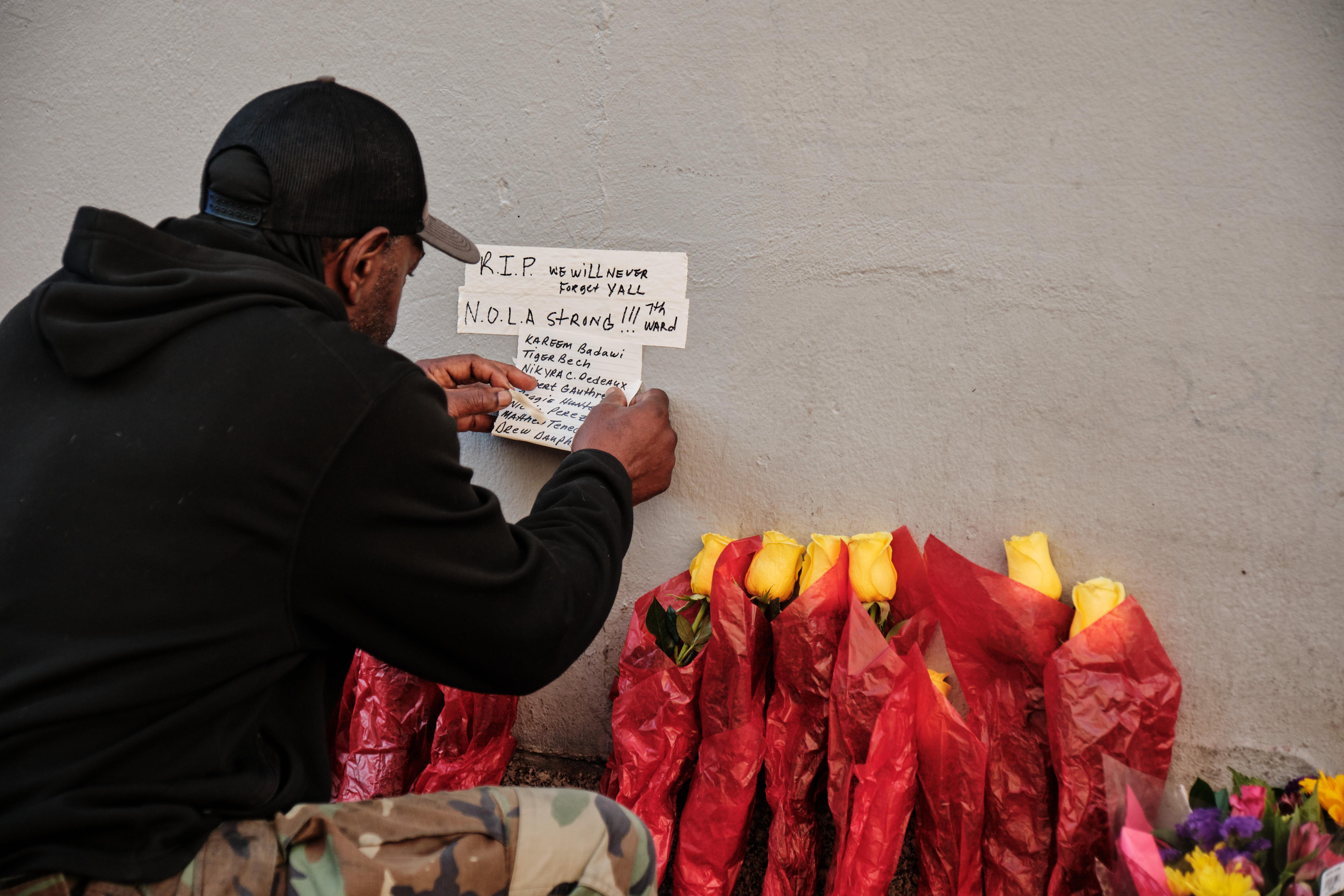 Un residente de Nueva Orleans cuelga un monumento escrito a mano cerca de un conjunto de flores en la calle Bourbon tras su reapertura al público en Nueva Orleans, Luisiana, EE.UU. (Foto Prensa Libre: AFP)