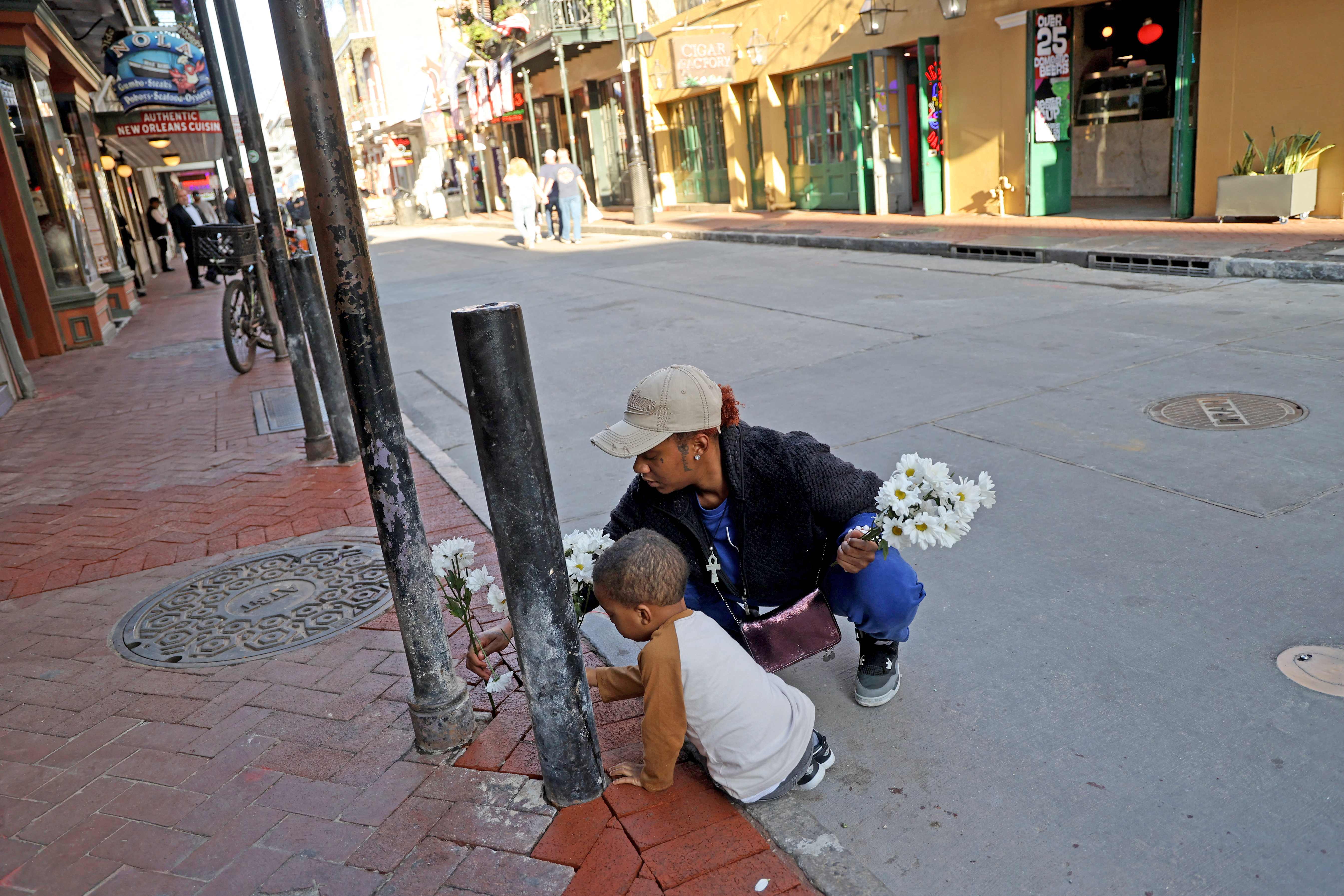 Mya Williams y Carter Hunt, colocan flores en la cuadra 100 de Bourbon Street un después del ataque que dejó 15 muertos y más de 30 heridos. (Foto Prensa Libre: AFP)