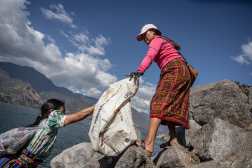 AME8377. SAN PEDRO LA LAGUNA (GUATEMALA), 08/02/2025.- Dos mujeres indígenas de san Pedro La Laguna sostienen un costal este sábado, en las playas del lago de Atitlán (Guatemala). En una jornada masiva de limpieza decenas de mujeres y buzos recolectaron 1.063 toneladas de desechos, como parte de las acciones para proteger el lago más profundo de Centroamérica y que anualmente recibe a más de 300.000 visitantes. EFE/ David Toro