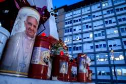 Rome (Italy), 22/02/2025.- A candle with the image of Pope Francis (L) sits at the foot of the statue of Pope St. John Paul II outside Gemelli University Hospital, where Pope Francis is battling pneumonia and a respiratory infection, in Rome, Italy, 22 February 2025. Pope Francis was hospitalized on 14 February due to a respiratory tract infection. (Papa, Italia, Roma) EFE/EPA/GIUSEPPE LAMI