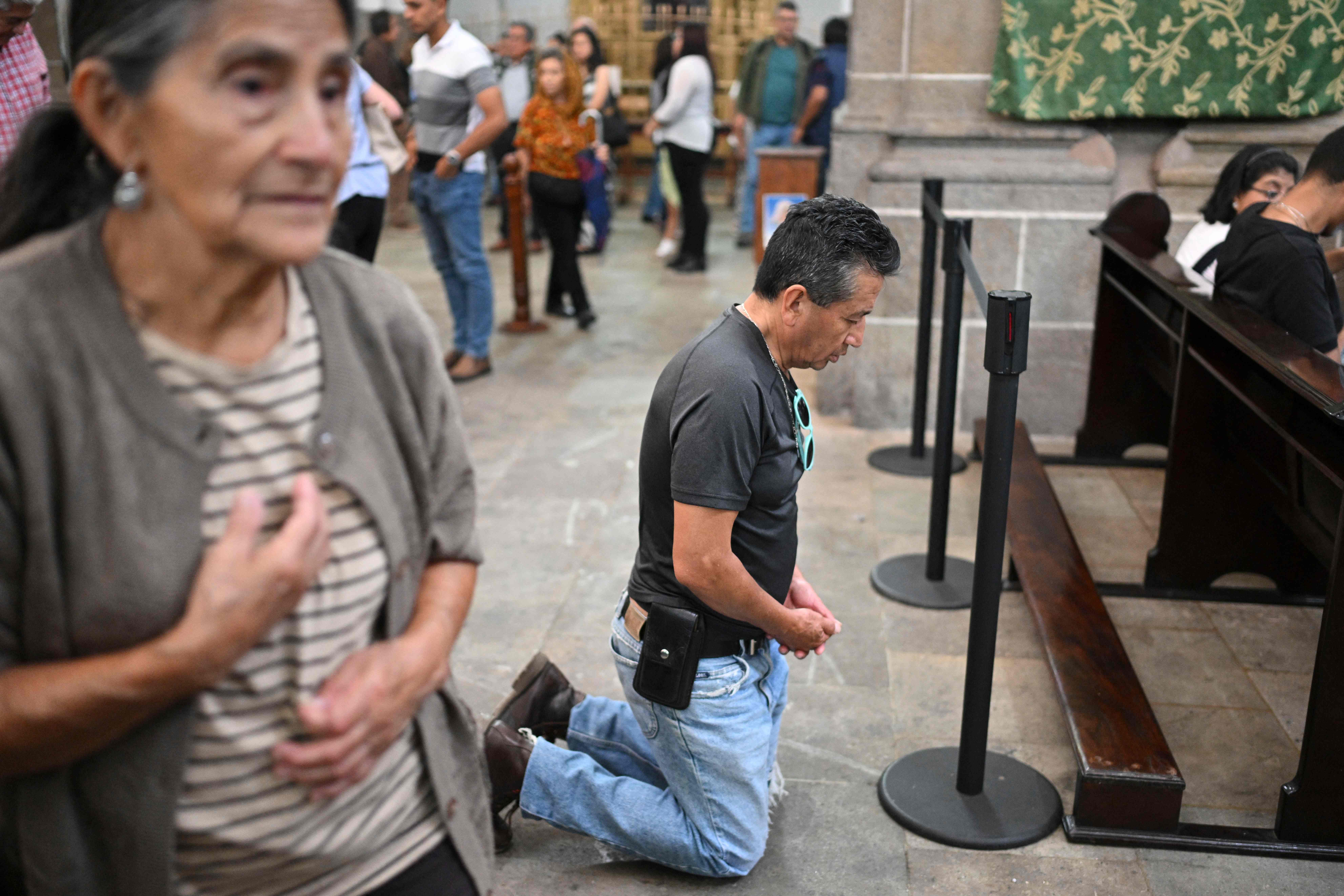 Un devoto reza de rodillas por la salud del Papa Francisco, la misa fue realizada en la catedral Metropolitana de la Ciudad de Guatemala. (Foto Prensa Libre: AFP)