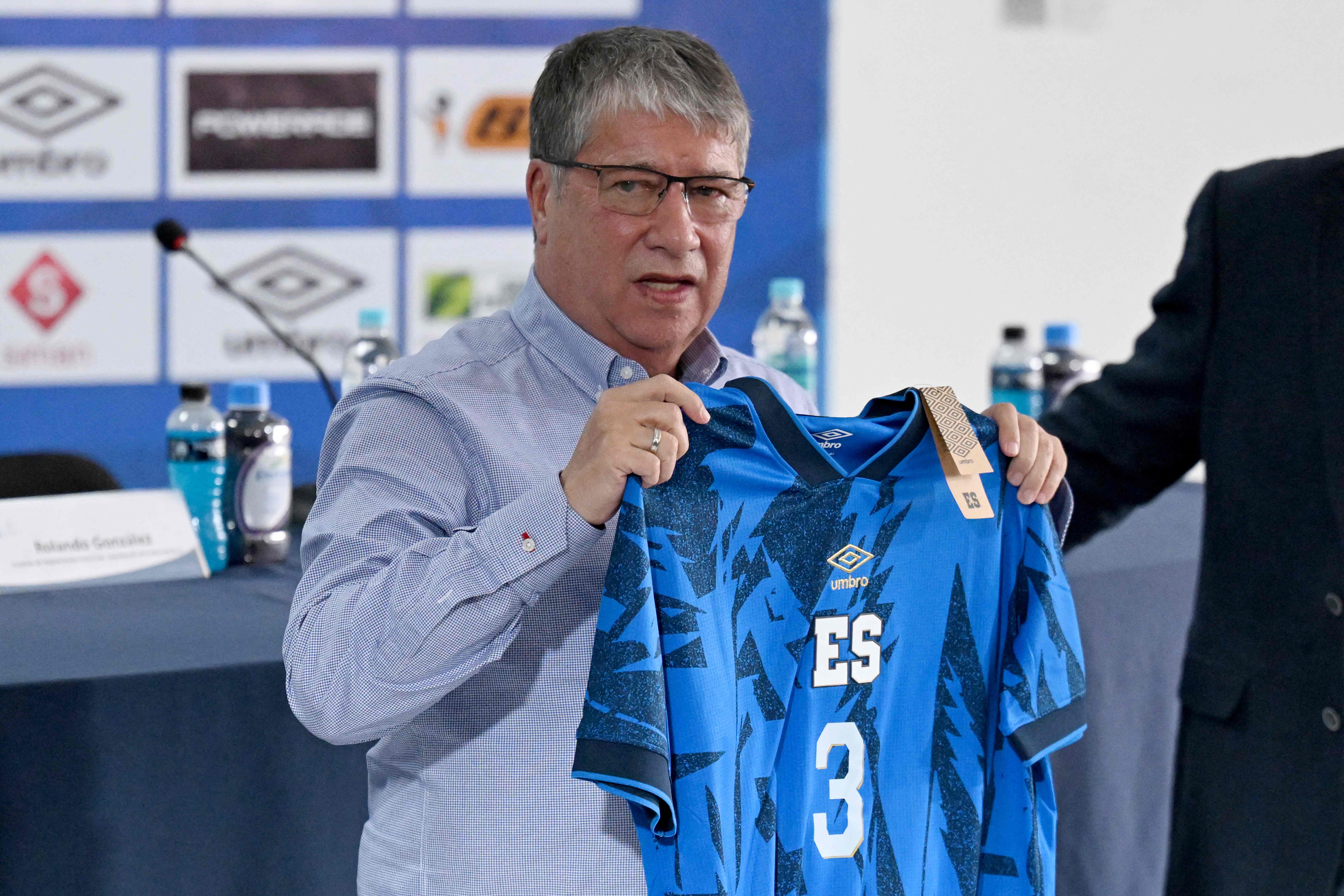 Colombian coach Hernán Darío Gómez displays a Salvadoran national football team t-shirt during his presentation as the new coach of the El Salvador football team in San Salvador on February 25, 2025. El Salvador's sports authorities announced Monday that Colombian Hernán Darío 'Bolillo' Gómez will be the new coach of the national soccer team in place of Spaniard David Dóniga Lara, whose contract was terminated. (Photo by Marvin RECINOS / AFP)