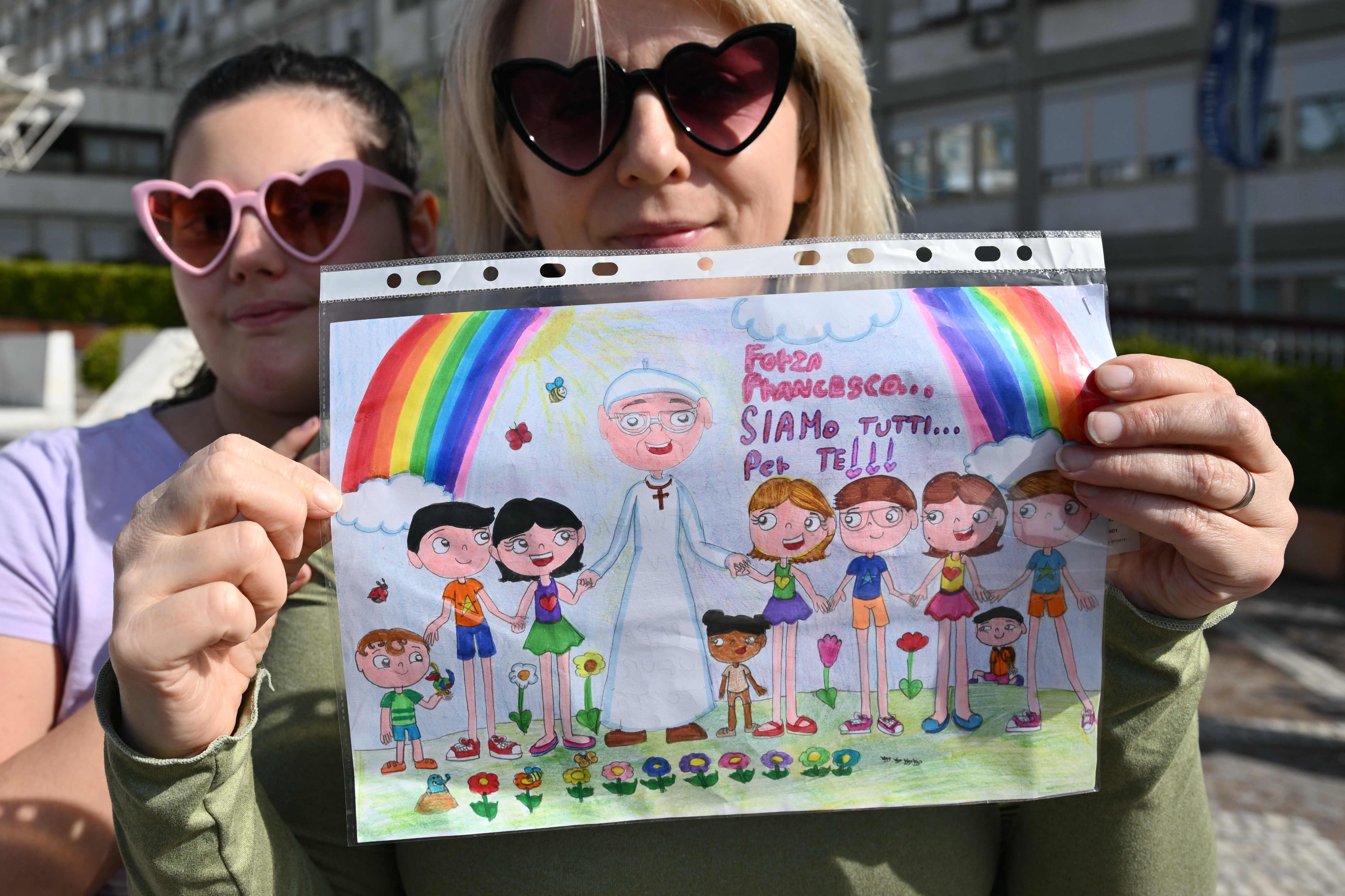 Fieles esperan noticias de la salud del Papa Francisco a las afueras del hospital donde se encuentra hospitalizado, Violetta de Polonia y su hija María, muestran un dibujo para el Papa. (Foto Prensa Libre: AFP)