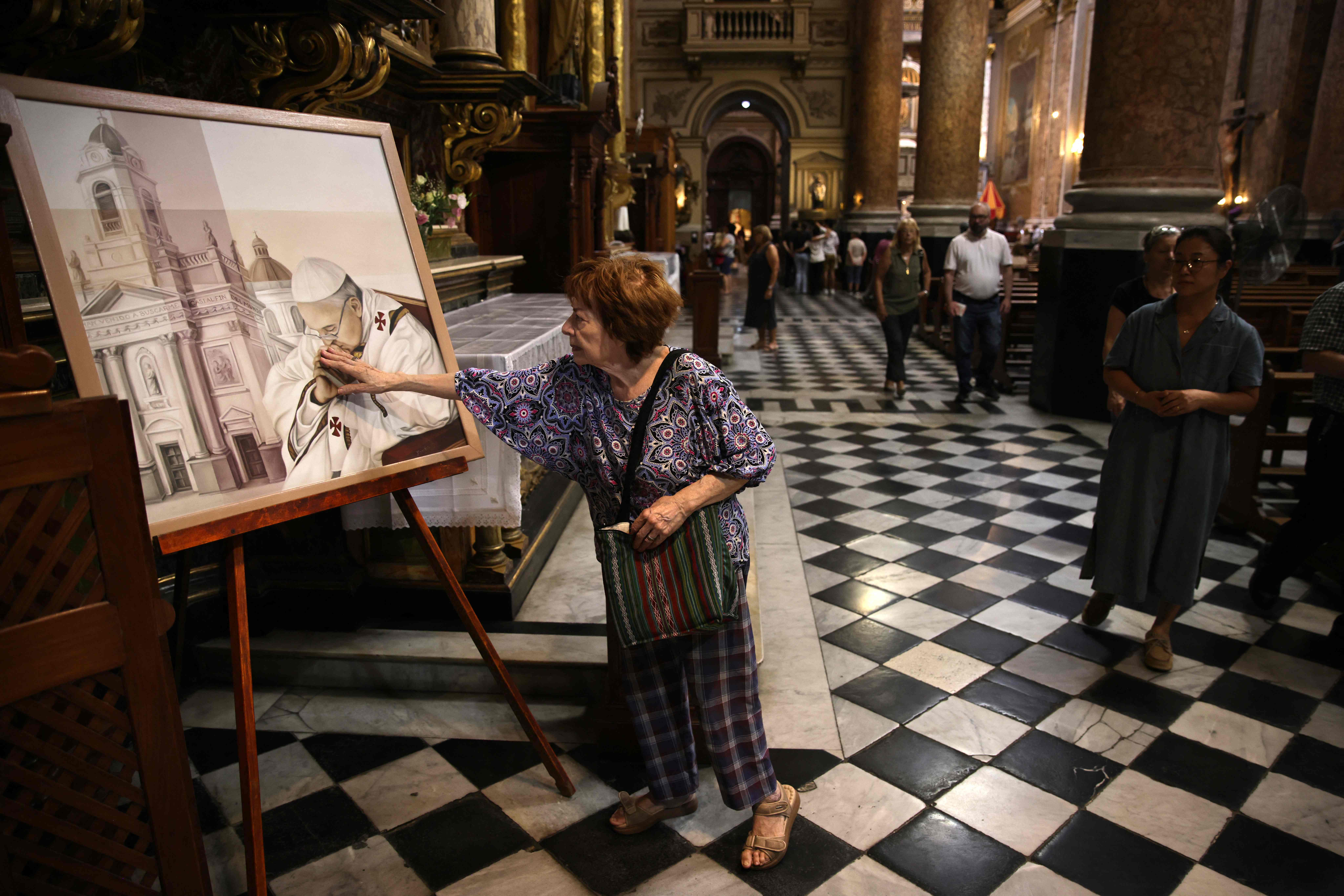 Una mujer toca un cuadro con el retrato del Papa Francisco en la Basílica de San José de Flores en Buenos Aires, Argentina (Foto Prensa Libre: AFP)