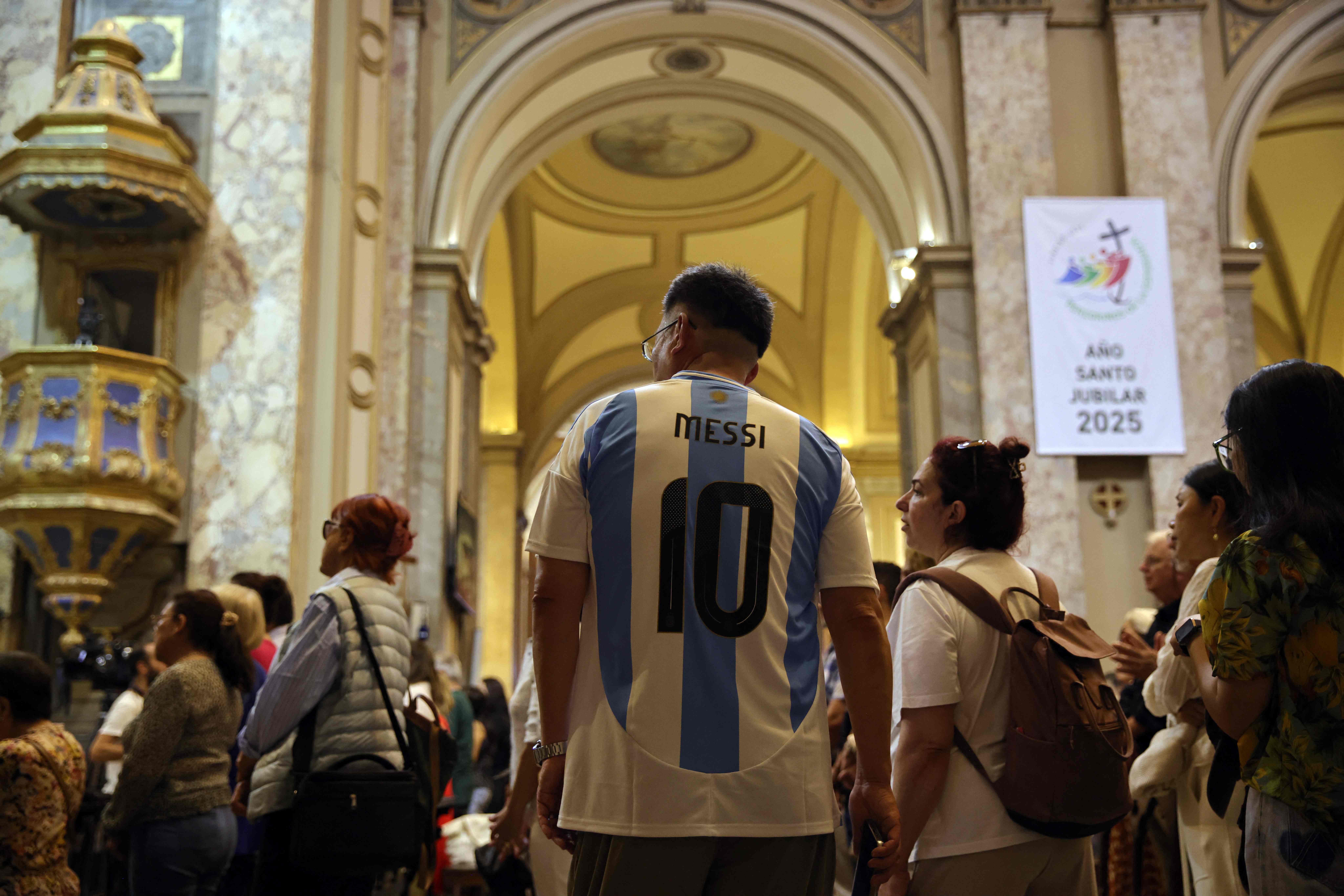 Un hombre vestido con la camiseta del delantero argentino Lionel Messi asiste a una misa, por la curación del Papa Francisco en la Catedral Metropolitana de Buenos Aires, Argentina. (Foto Prensa Libre: AFP)